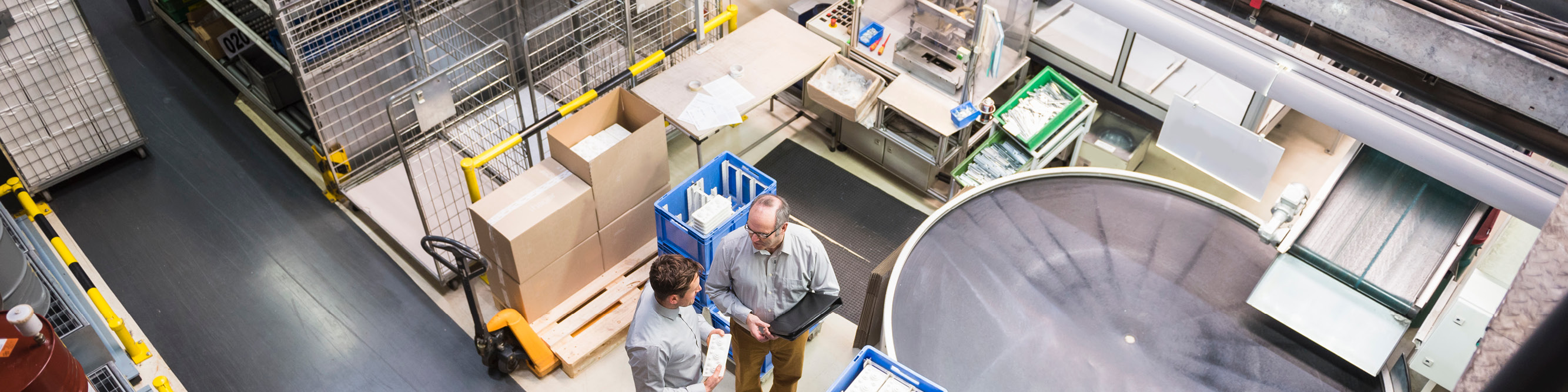 Bovenaanzicht van medewerkers die een productieproces bespreken in een fabriek als onderdeel van een levenscyclusanalyse en EPD