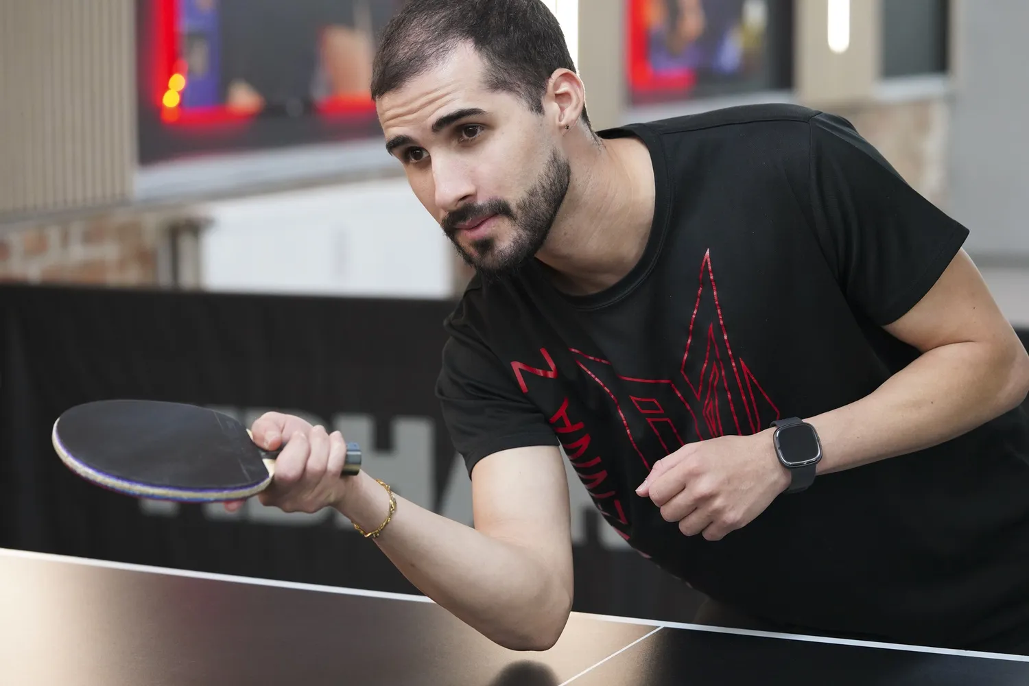 Junger Mann spielt Tischtennis und hält konzentriert einen Tischtennisschläger in der Hand.