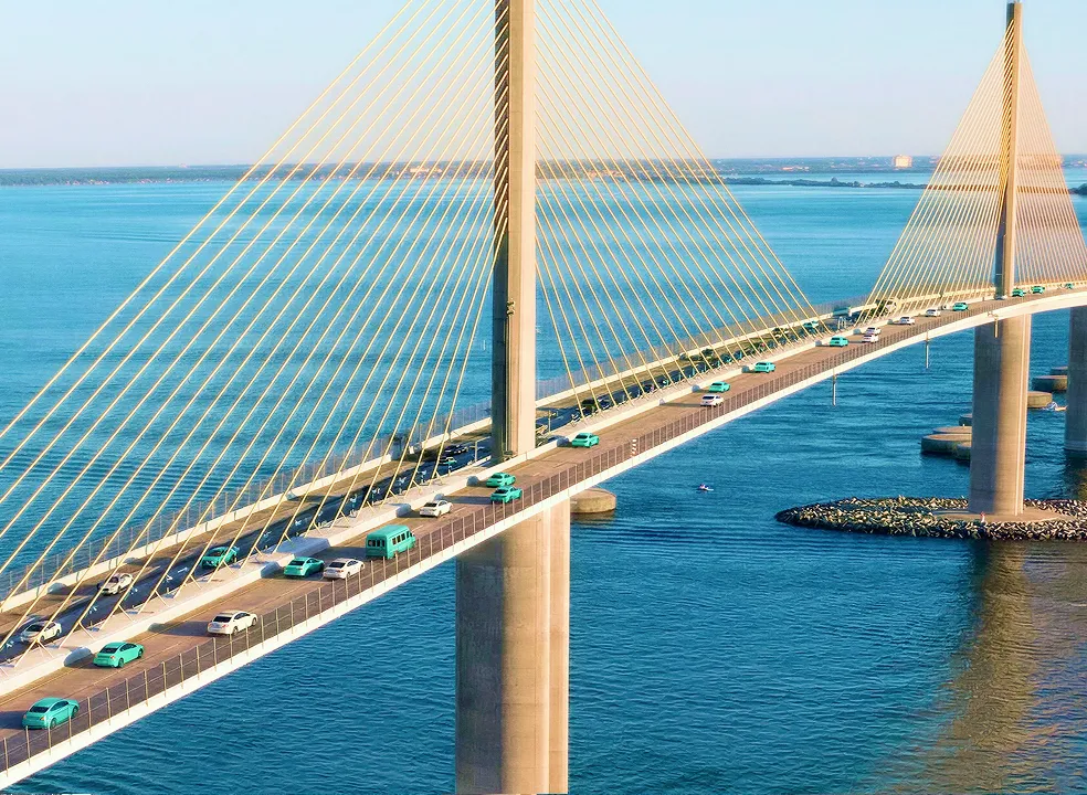 Cable-stayed bridge over blue water with several vehicles traveling across it under a clear sky.