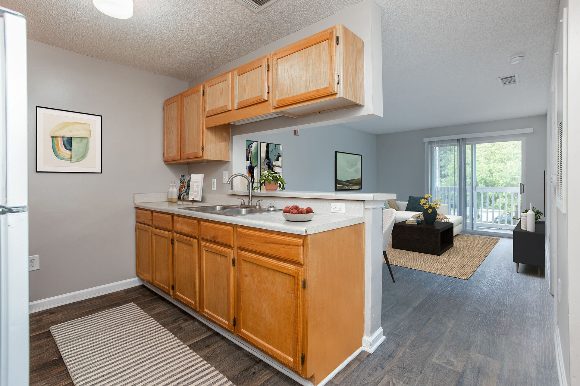 Kitchen with brown cabinets with view of Virtually Staged living area with sofa, table, and chairs