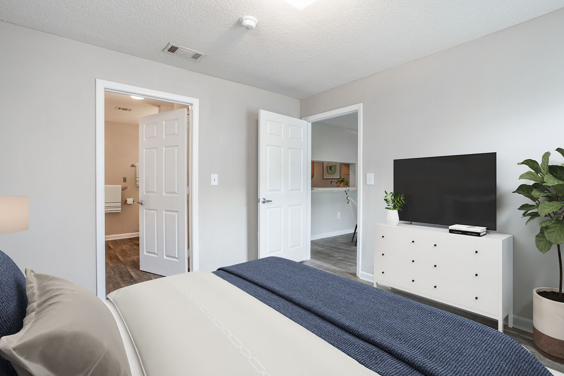 Virtual staged bedroom with bed, tv, and plant