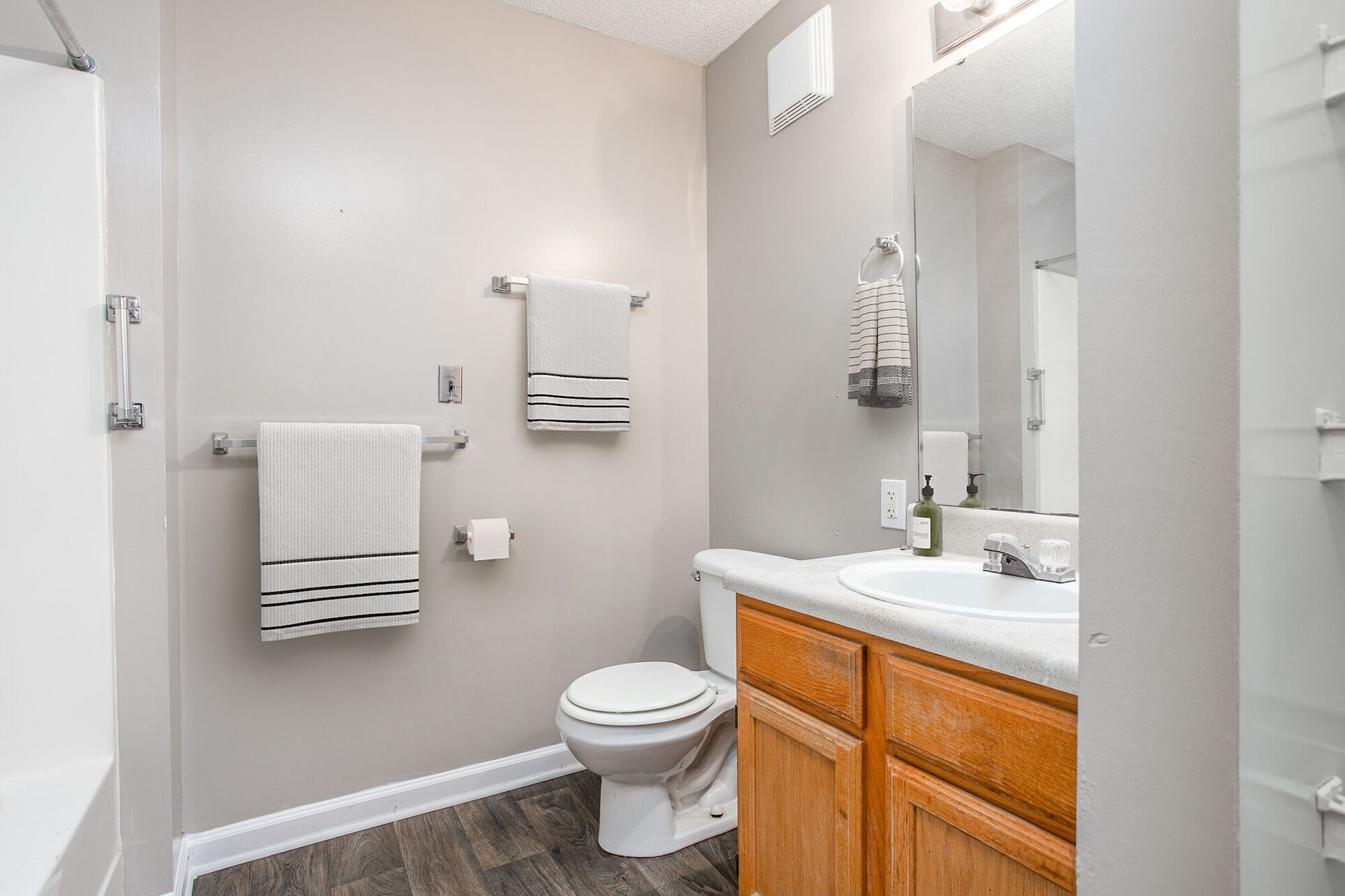 Bathroom with tub, toliet, brown cabinets