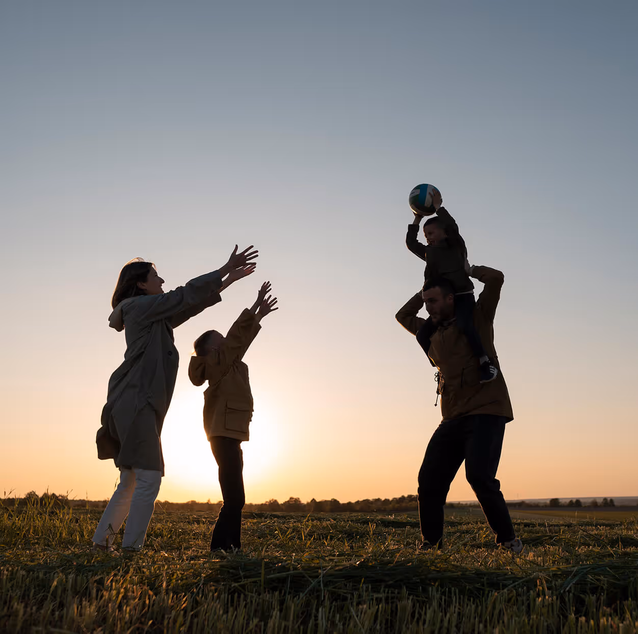 Familia feliz jugando al atardecer en el campo