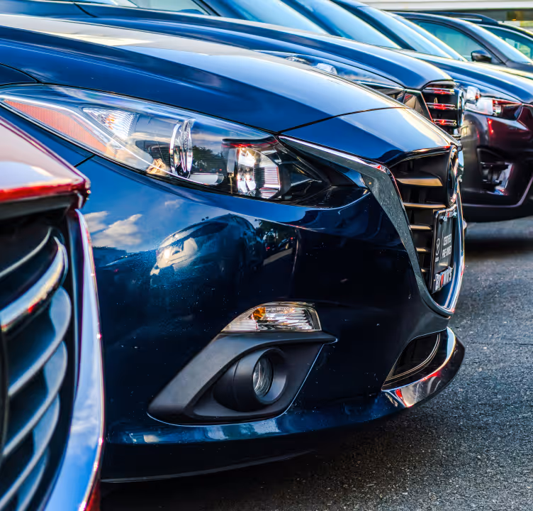 Gros plan sur la partie avant d'une voiture bleue garée en rangée avec d'autres voitures similaires.