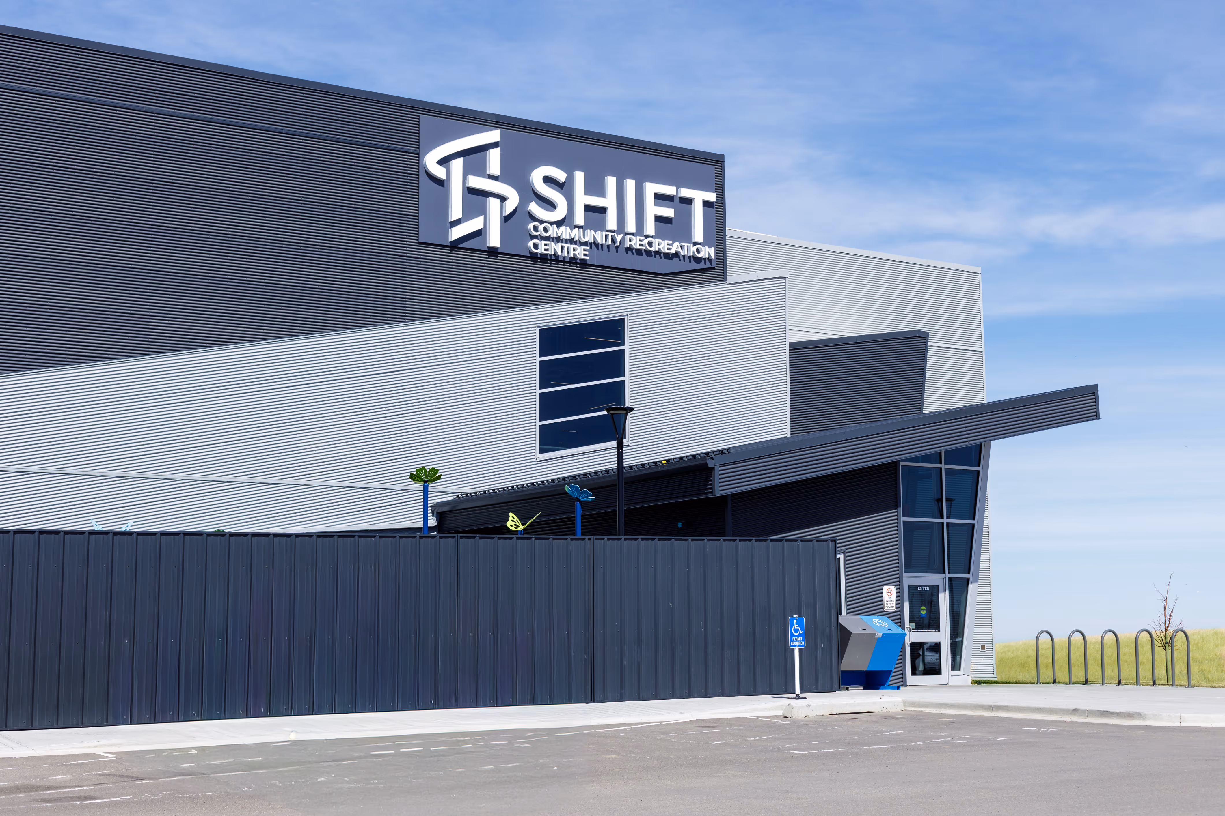 Modern community recreation centre building named SHIFT with blue sky background.