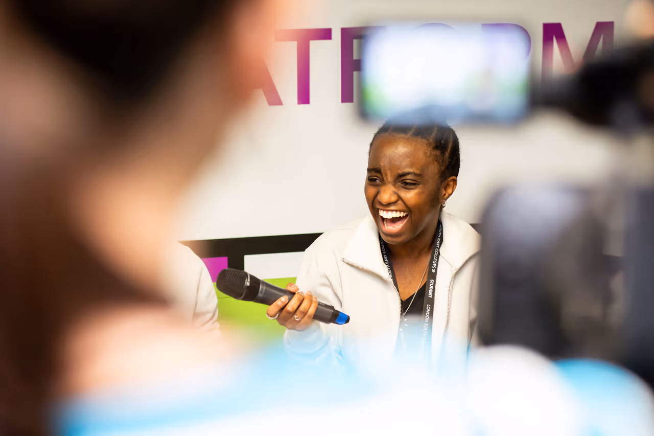 Woman laughing while holding a microphone during an interview or recording session.