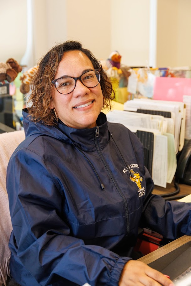 Staff member smiling at desk in classroom