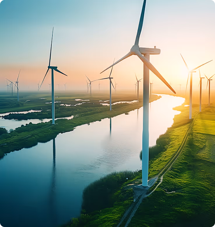 Wind turbines along a river at sunset generating renewable energy.