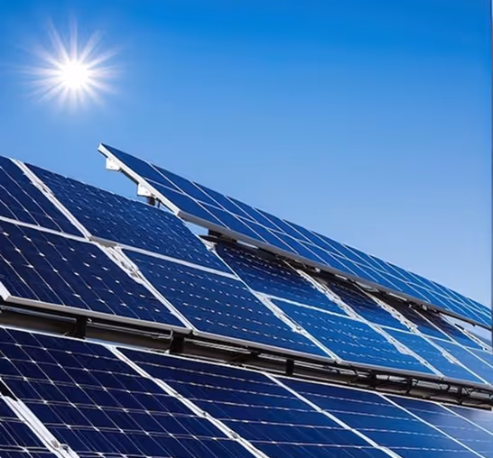 Solar panels angled towards a bright sun in a clear blue sky.