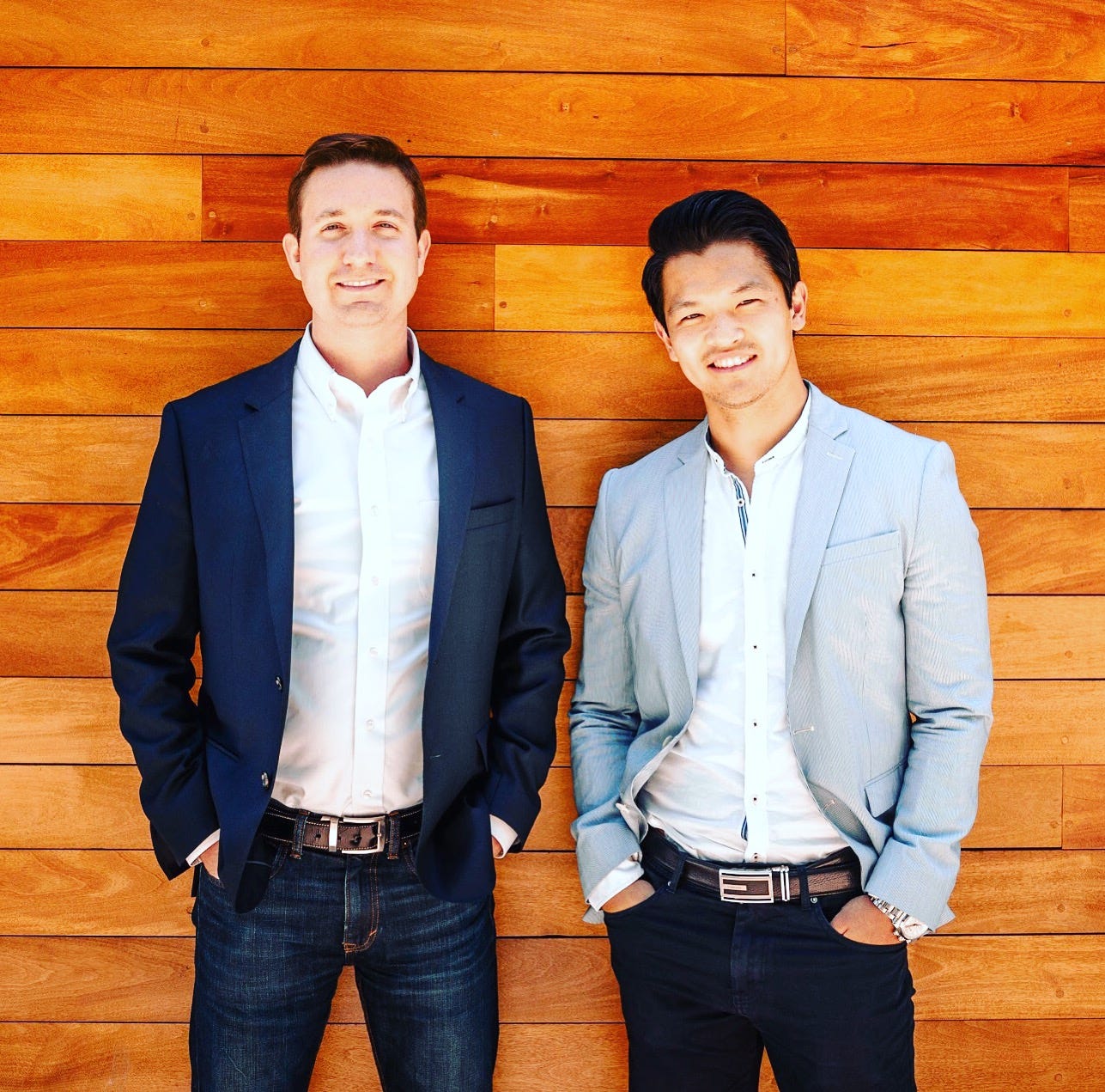 Two men wearing blazers stand against a wooden wall in the photo accompanying Bluwhale's funding announcement.