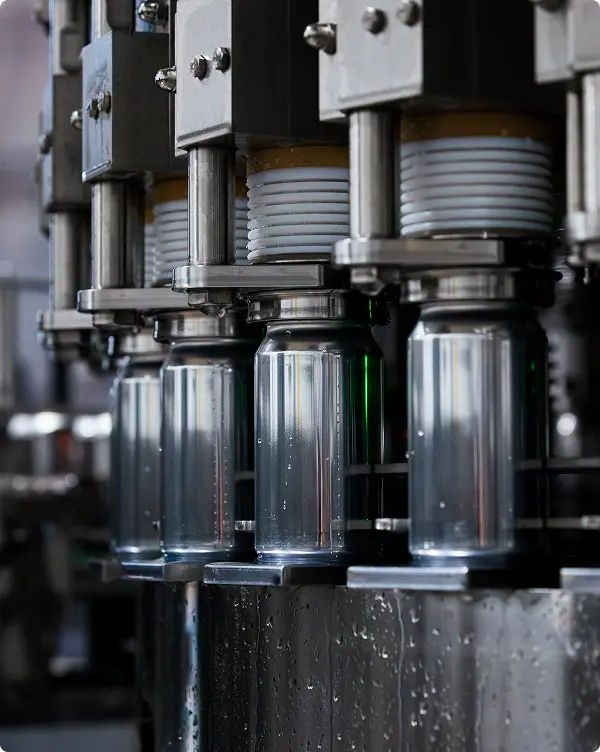 Industrial bottling machine in a factory setting, with multiple bottles being filled or capped simultaneously by automated equipment.