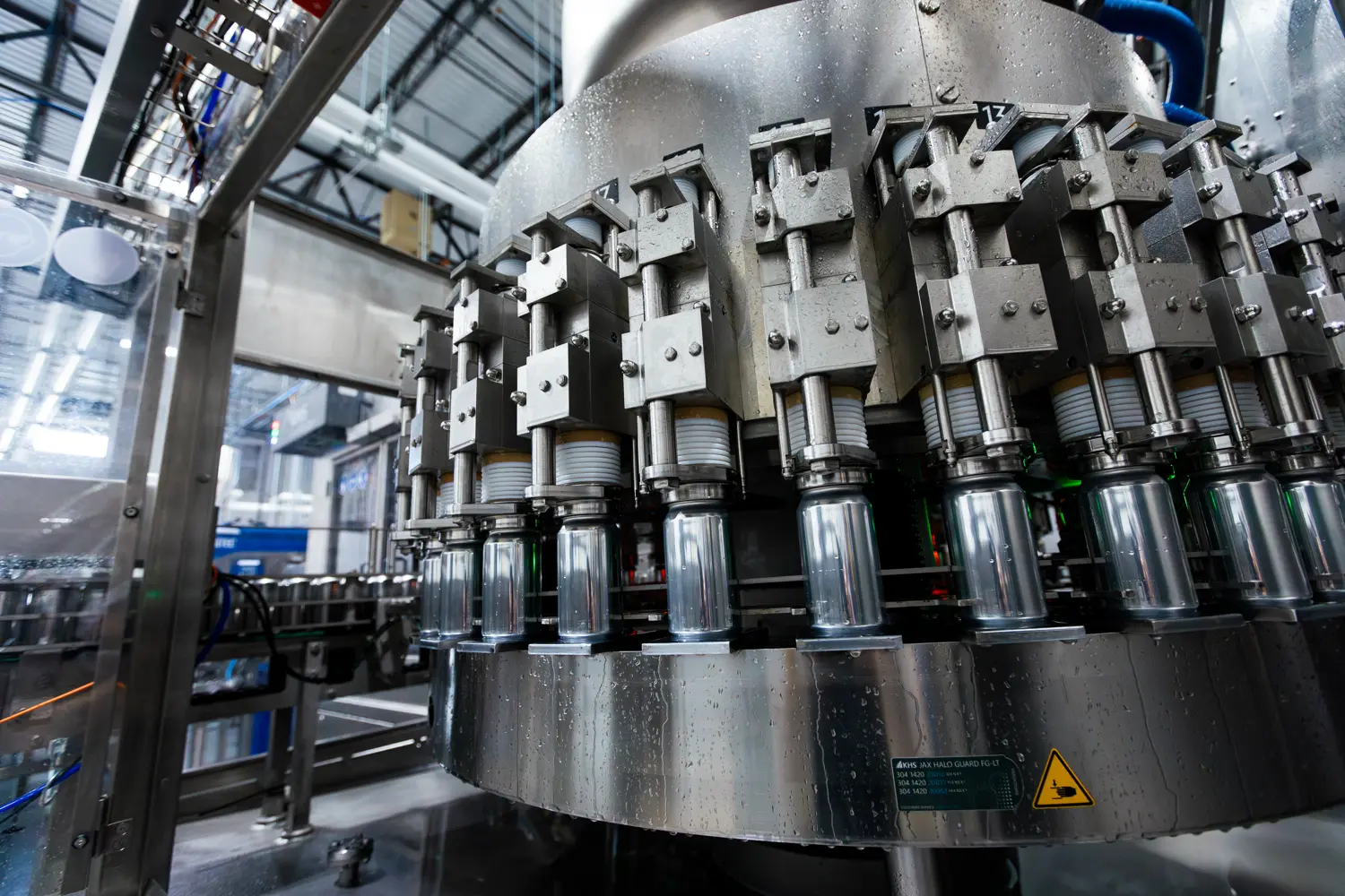 Industrial bottling machine in a factory setting, with multiple bottles being filled or capped simultaneously by automated equipment.