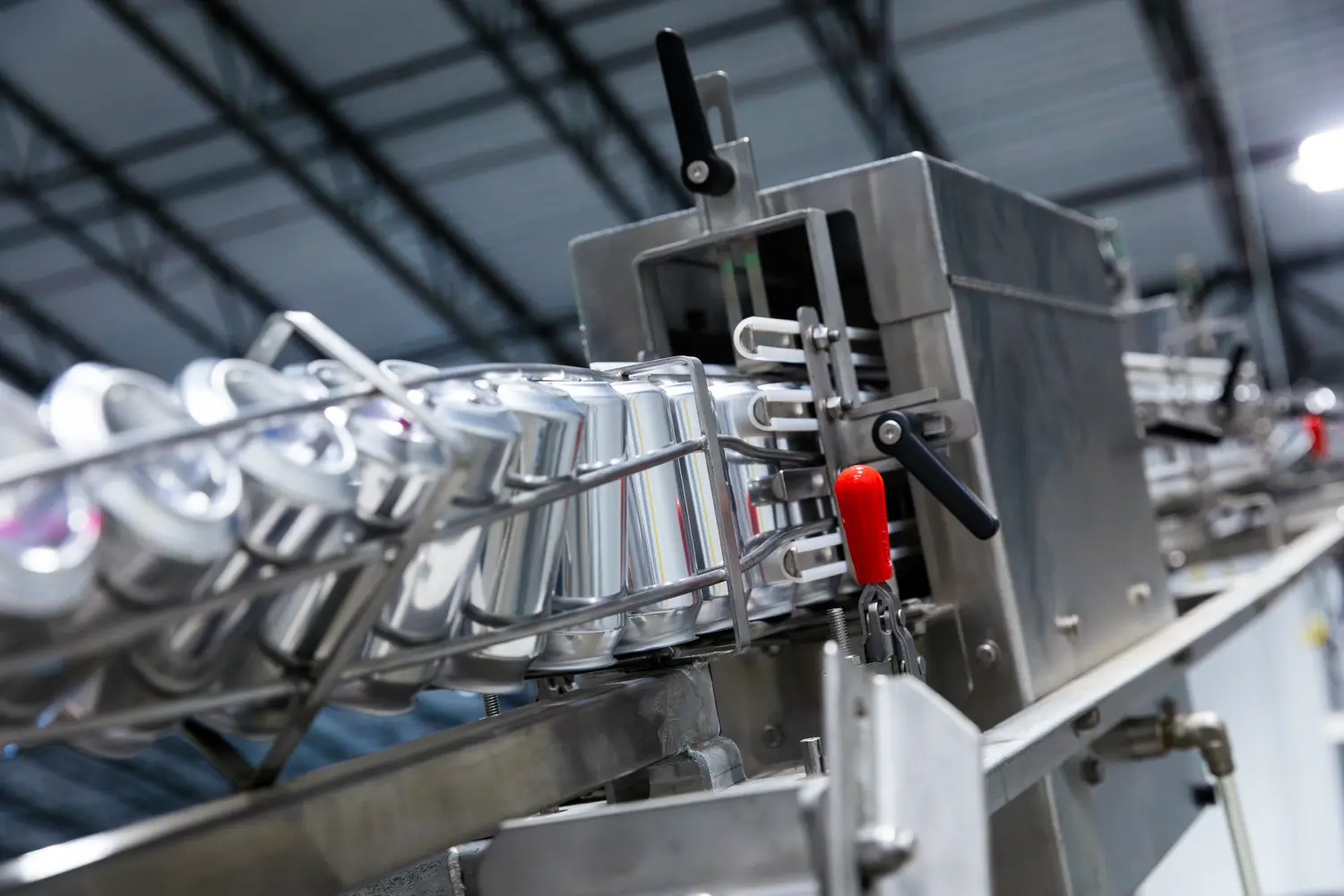 Aluminum cans move along a conveyor belt in an industrial production facility.