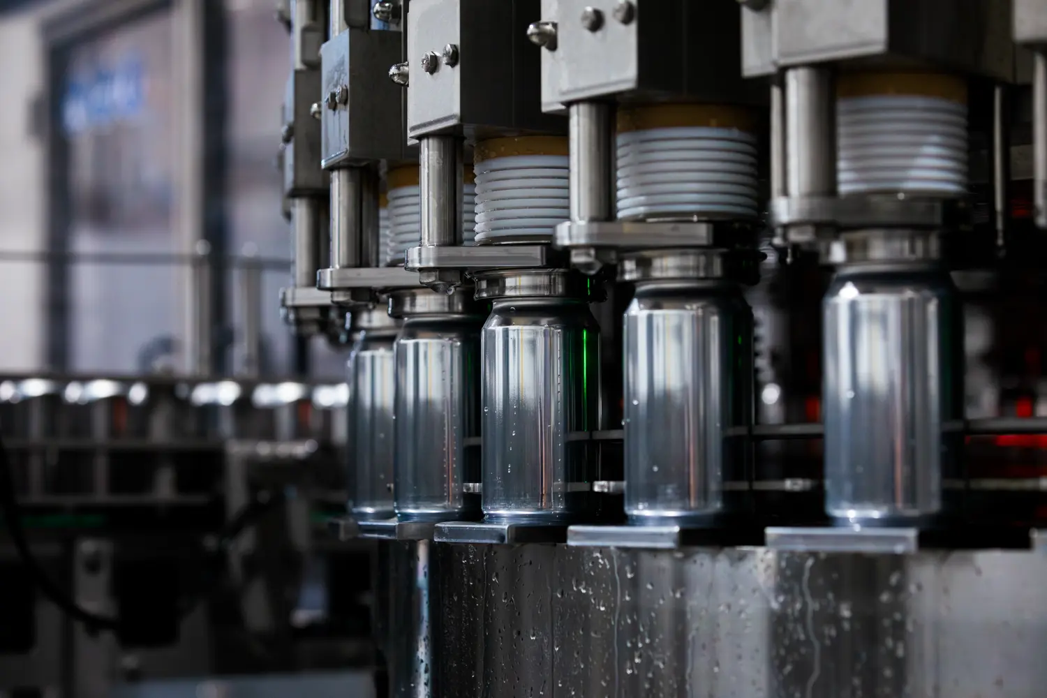 Industrial bottling machine in a factory setting, with multiple bottles being filled or capped simultaneously by automated equipment.