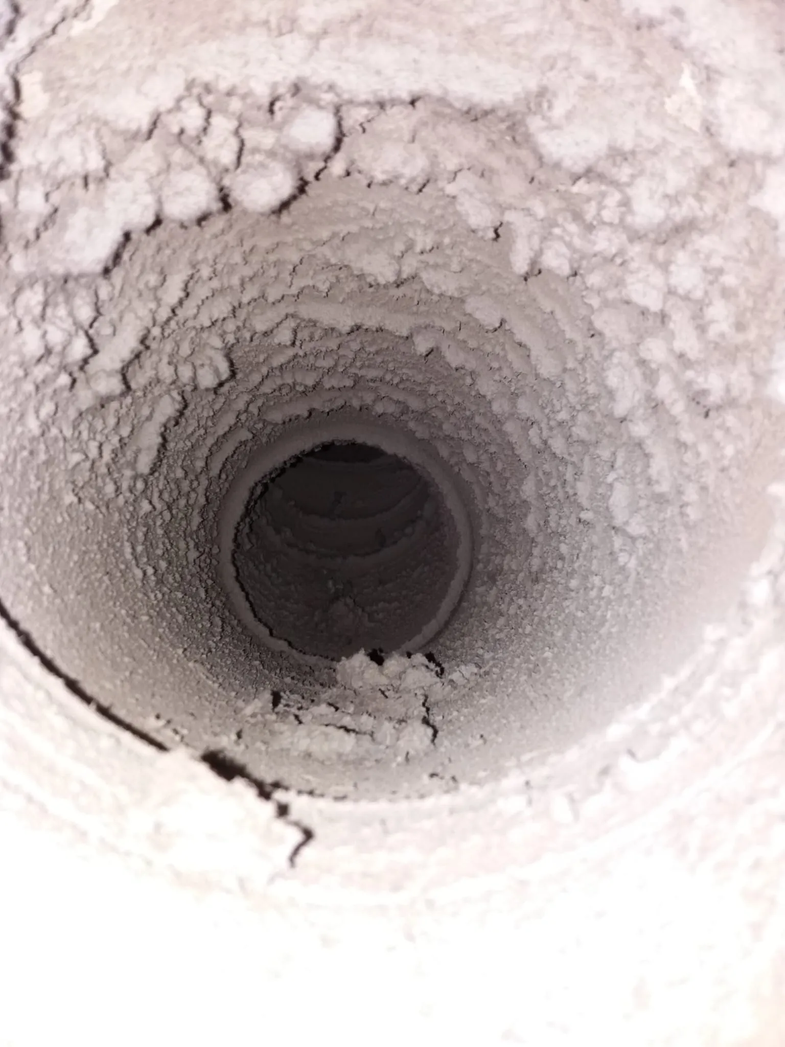 Kuva näyttää sisältäpäin likaisen, pölyisen putken, jonka seinämät ovat epätasaiset ja harmaat. Valo tulee putken päästä.