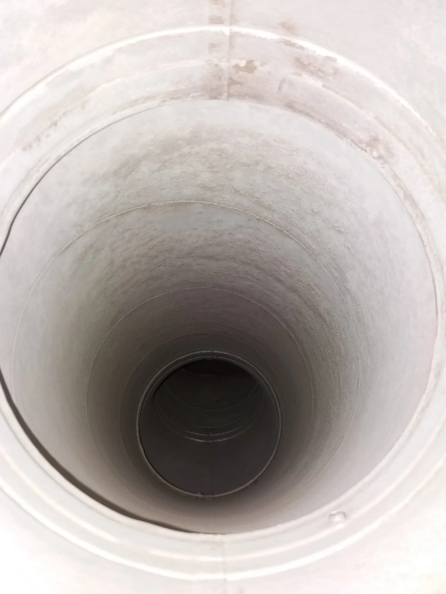 Valkoinen, pyöreä putki, jossa on tumma aukko päässä ja epätasainen valaistus.