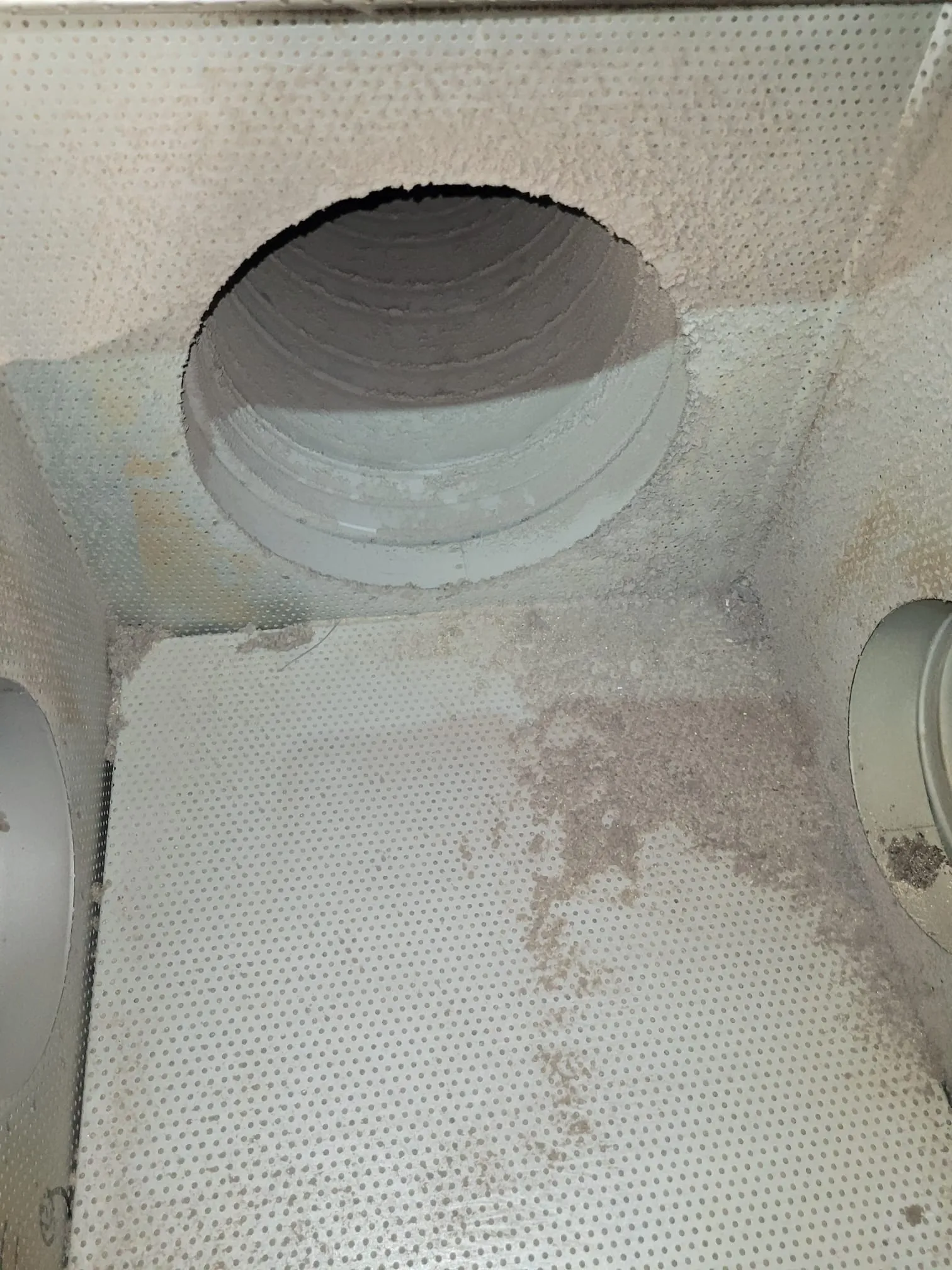 Likaista, rei'itettyä metallipintaa, jossa on pyöreitä aukkoja ja pölyä.