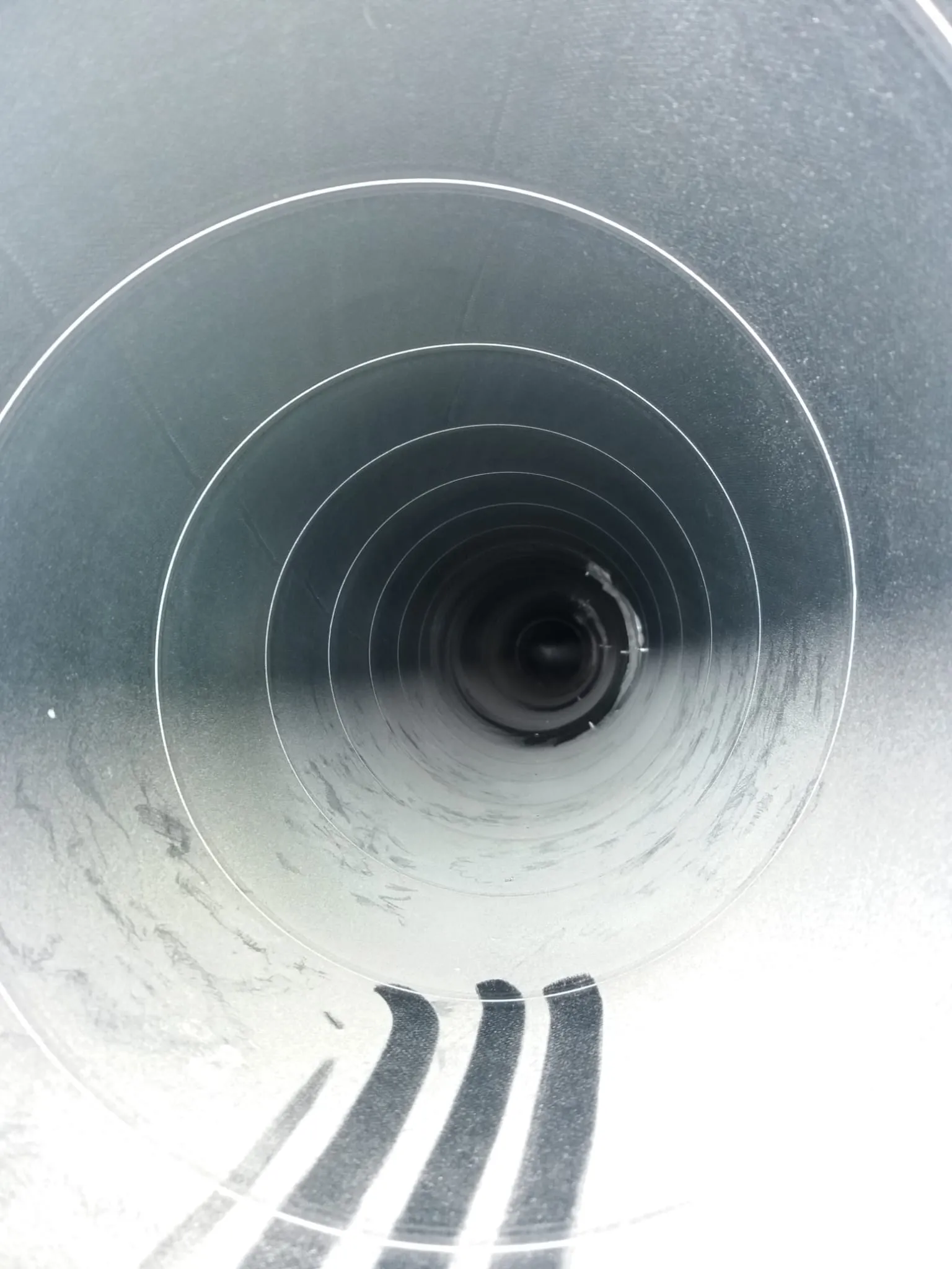 Metallinen putki, jossa on pyöreitä muotoja ja tumma pää, valaistus on kirkas ja heijastava.