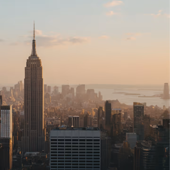 View of New York City skyline at sunset with the Empire State Building prominently in the foreground.