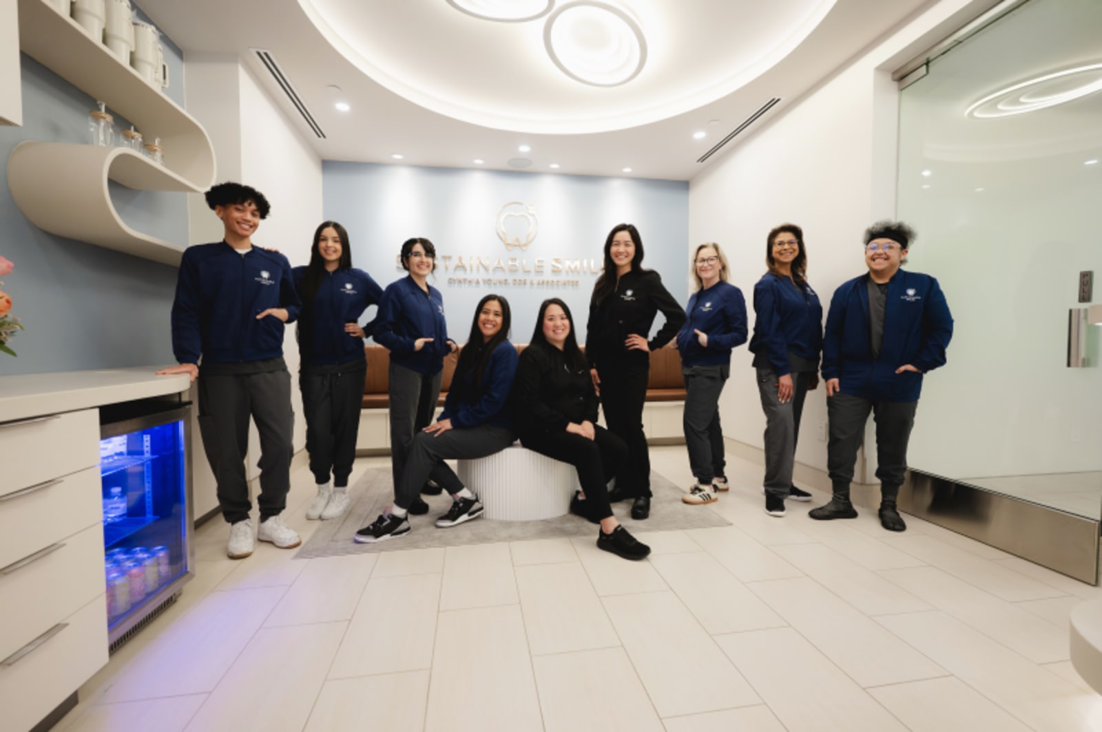 Diverse dental team of 10 professionals standing together in modern clinic reception area