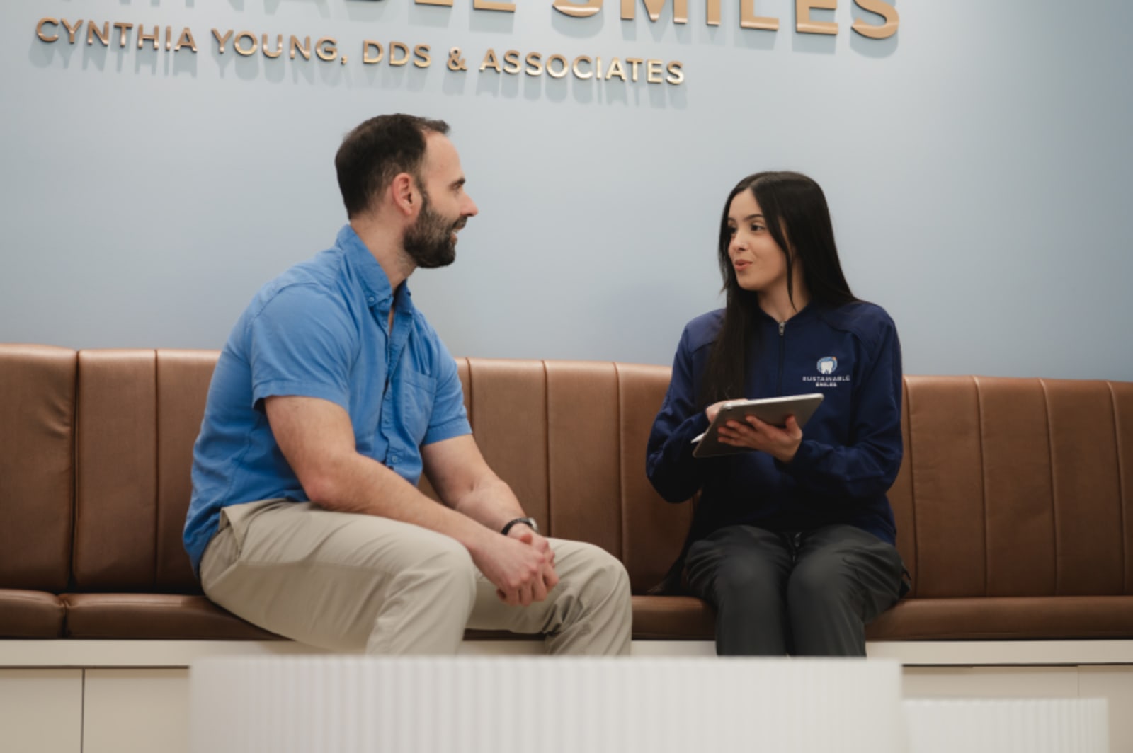 Male dentist consulting with female patient in modern dental office setting
