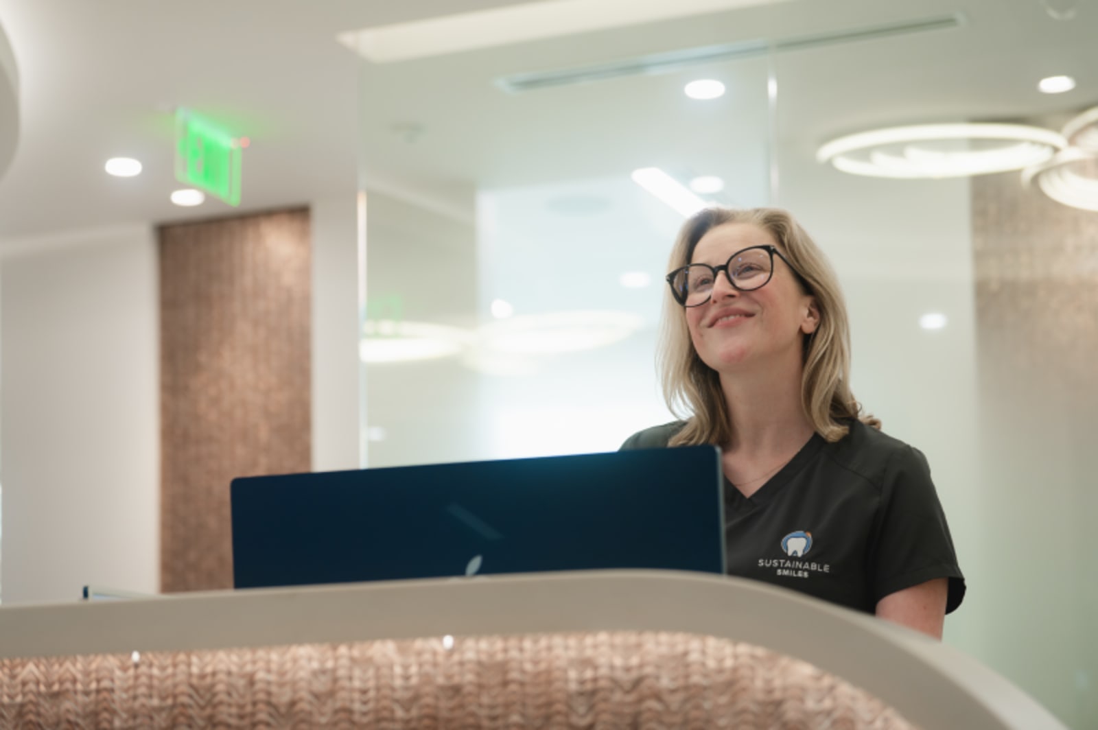 Team member at Sustainable Smiles reception desk smiling and greeting patient