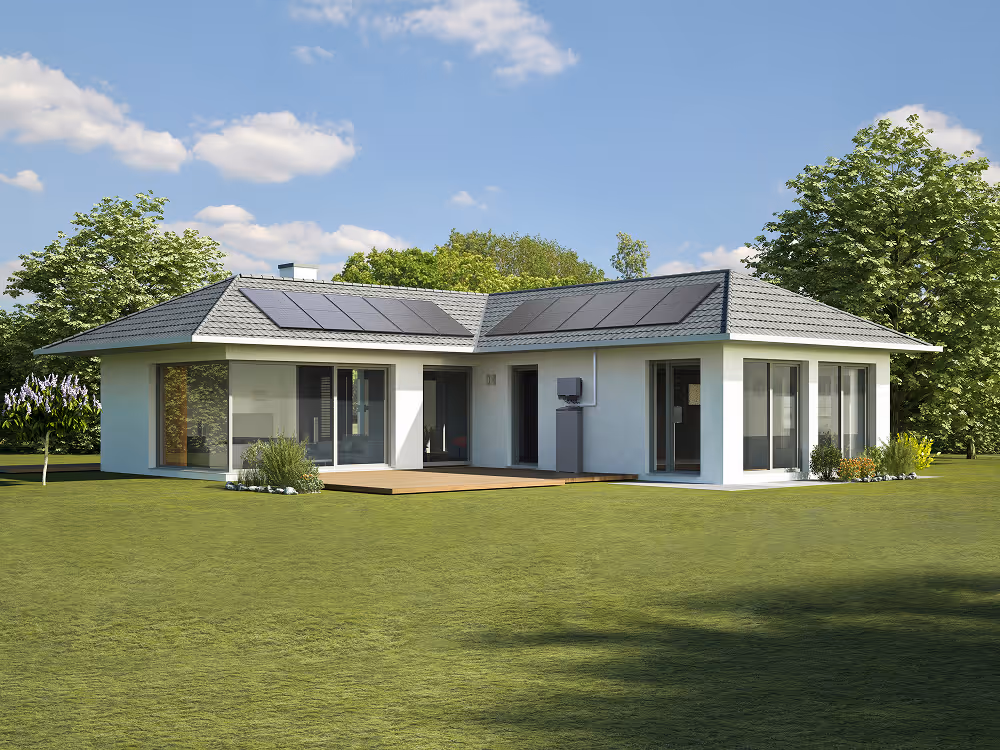 Single-story modern white house with solar panels on roof and large glass windows, surrounded by green lawn.