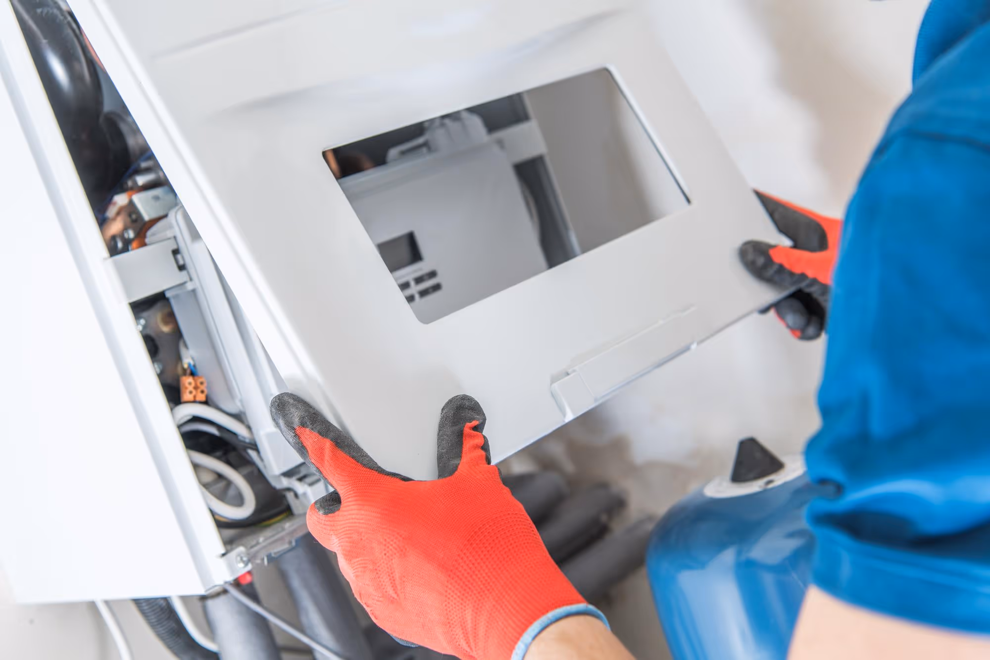 Person wearing red gloves removing panel from an electrical inverter box for maintenance.