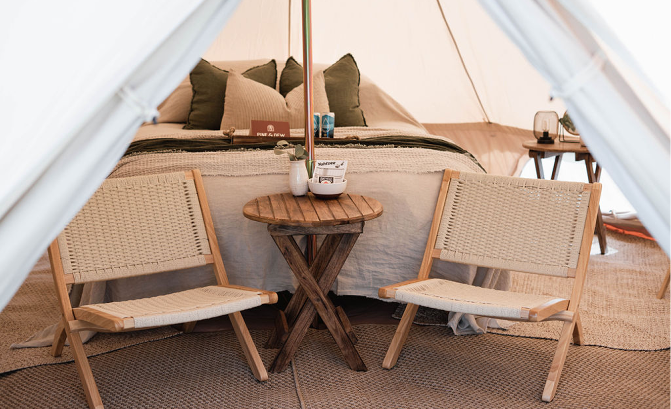 Chairs and table near bed in tent