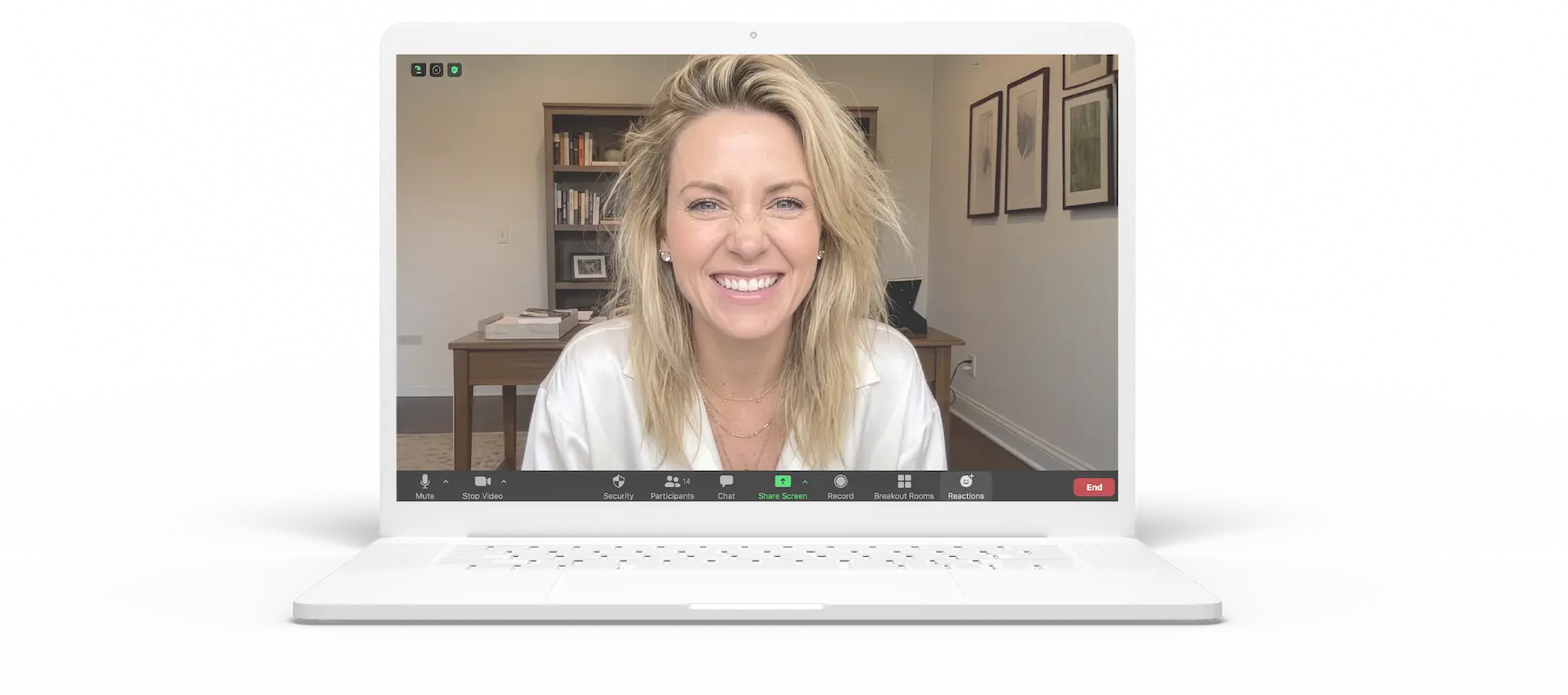 Smiling woman with blonde hair on a video call shown on a white laptop screen.