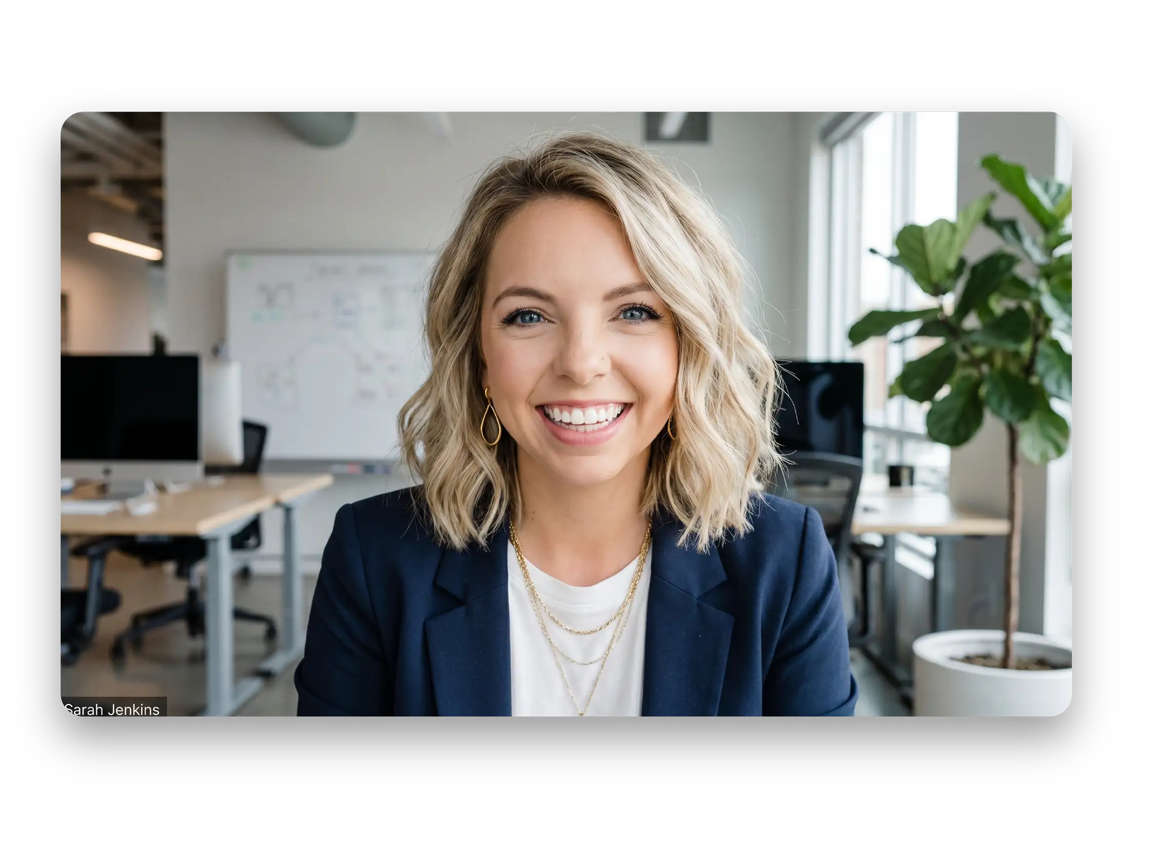 Smiling blonde woman with wavy hair in a navy blazer in a modern office space.