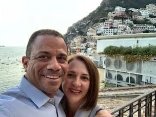 David B, smiling outside with arm around another person