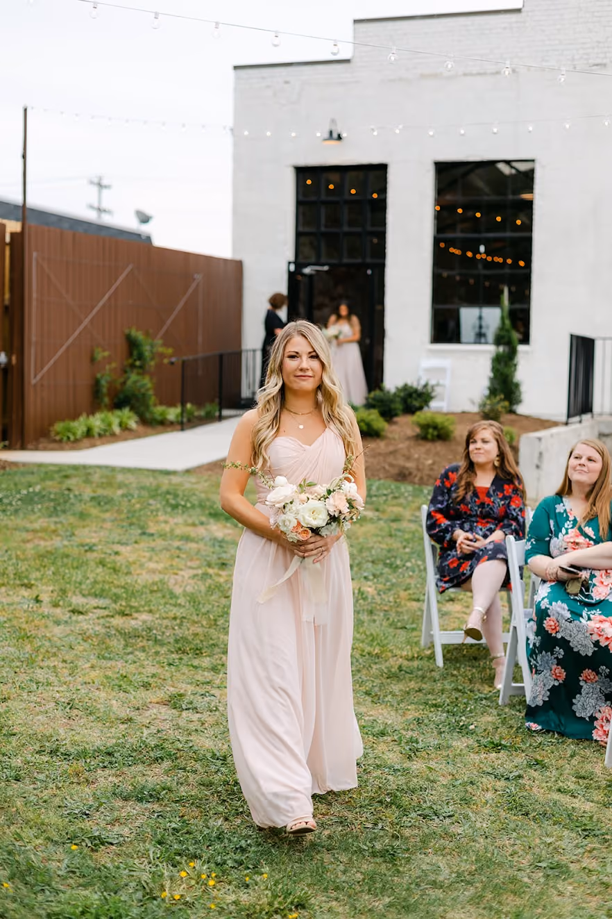 Bride and groom holding hands and running outdoors under string lights at dusk.