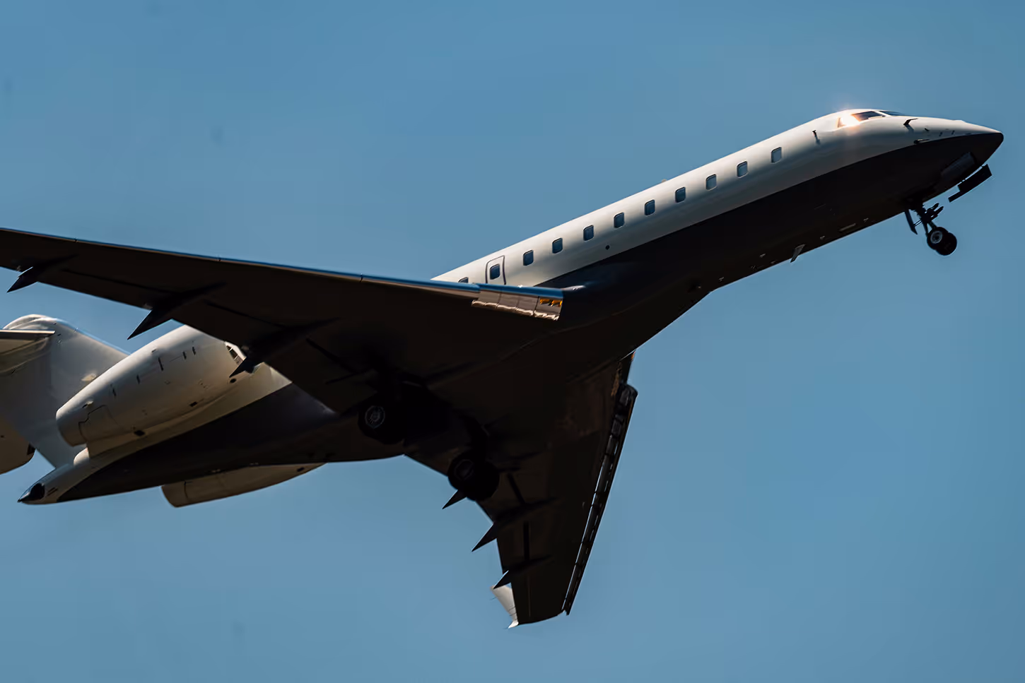 Passenger airplane taking off against a clear blue sky with landing gear extended.