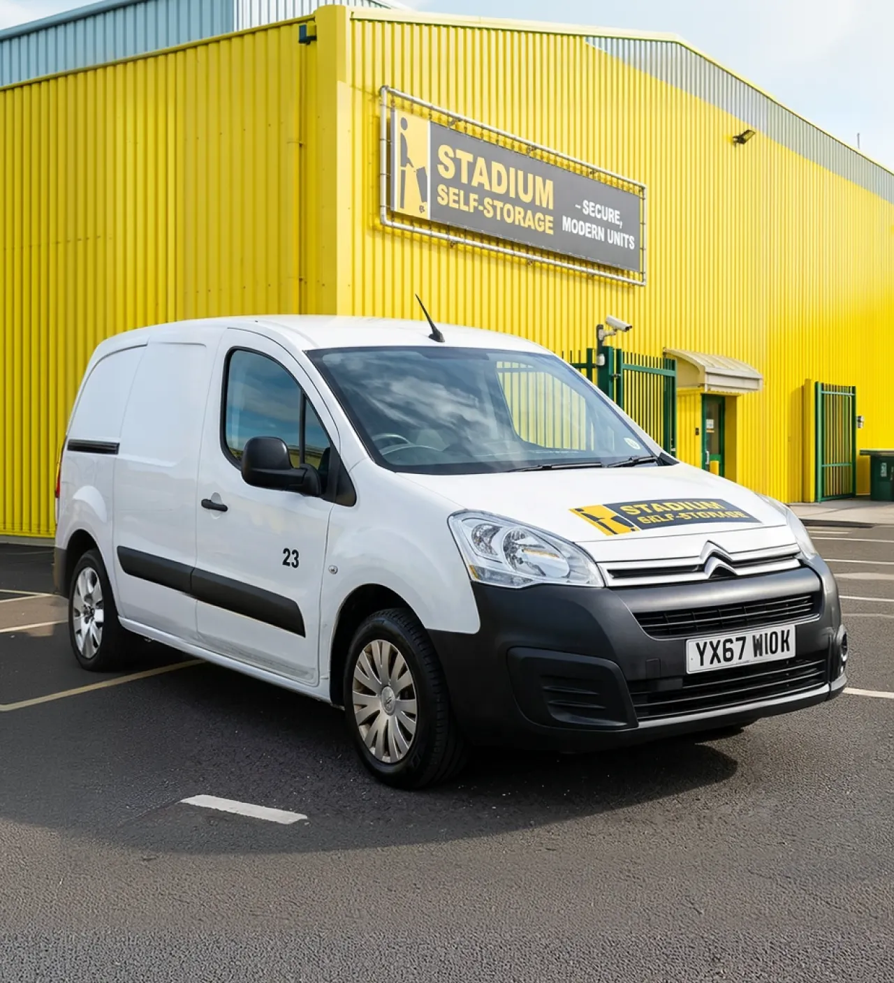 White Citroën van with Stadium Self-Storage logo parked outside a yellow storage facility building.