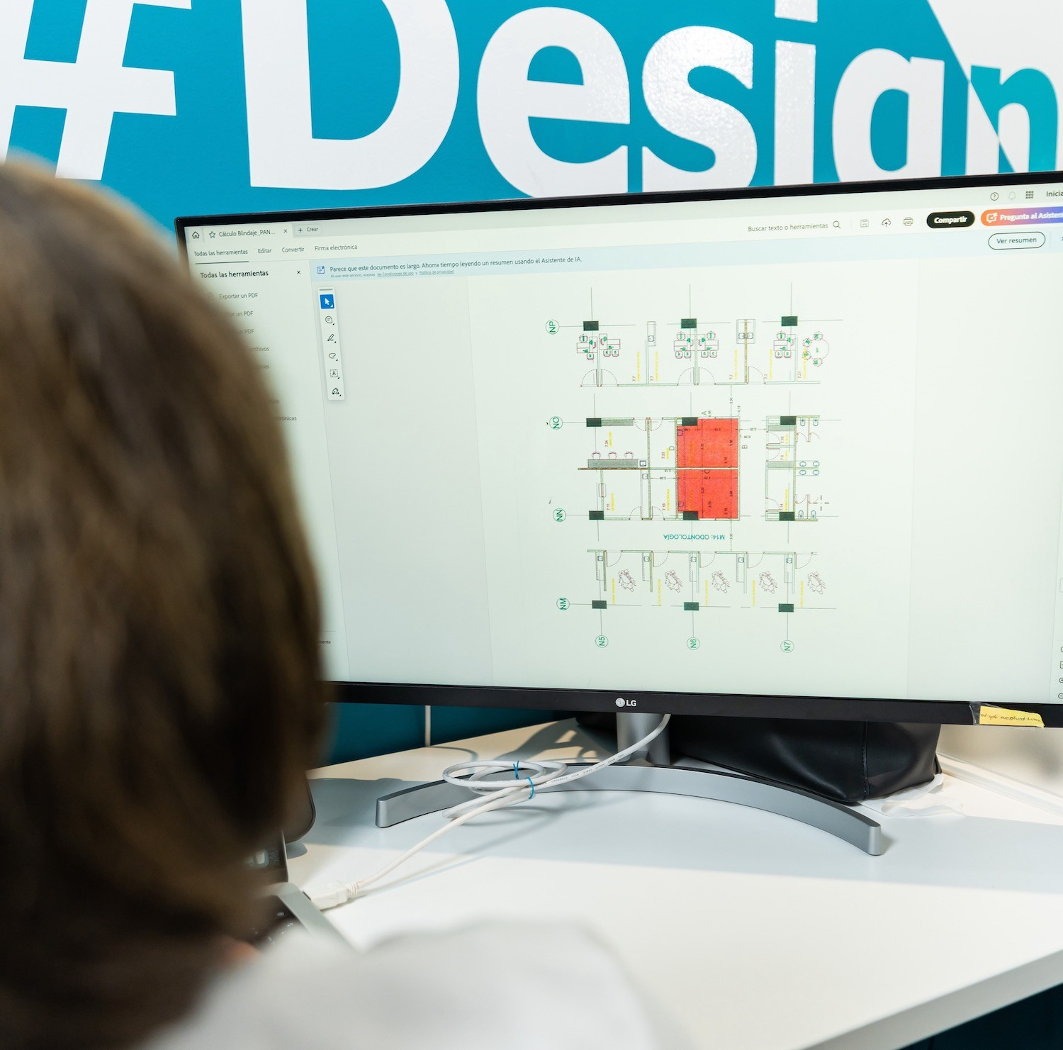Una persona observa un plano de una sala radiológica en un monitor LG de gran tamaño, frente a una pared azul en la que se ve parcialmente la palabra «Design».