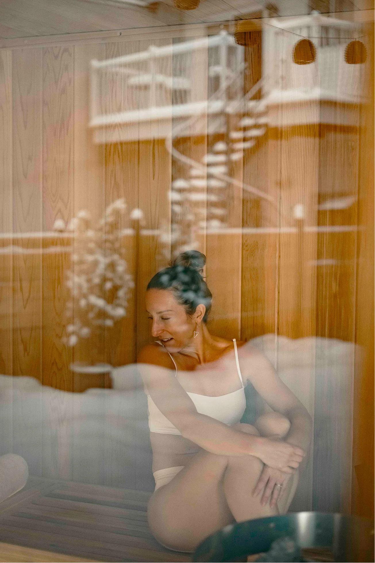 Guest laughing inside the cedar sauna, seen through the steamed glass door at La Maison Ralia