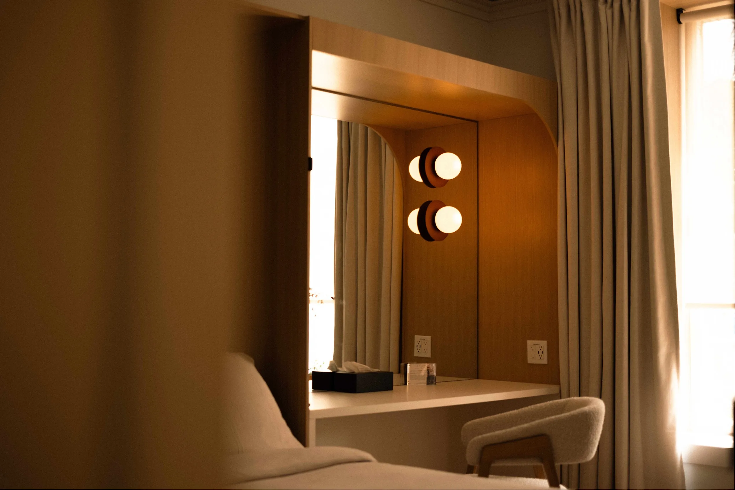 Guest room vanity with globe sconces and warm evening light at La Maison Ralia's Montreal boutique hotel