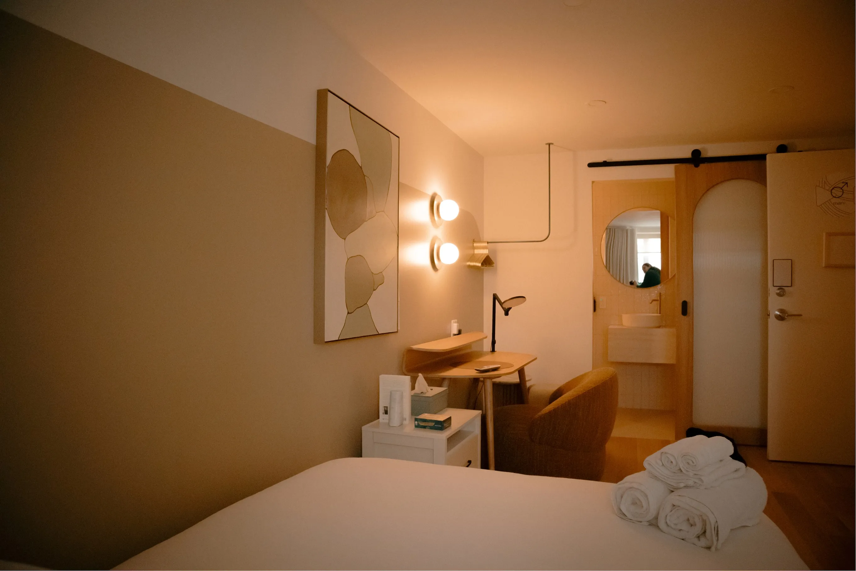 Guest room at La Maison Ralia's Montreal boutique hotel with rolled towels on the bed and an ensuite bathroom