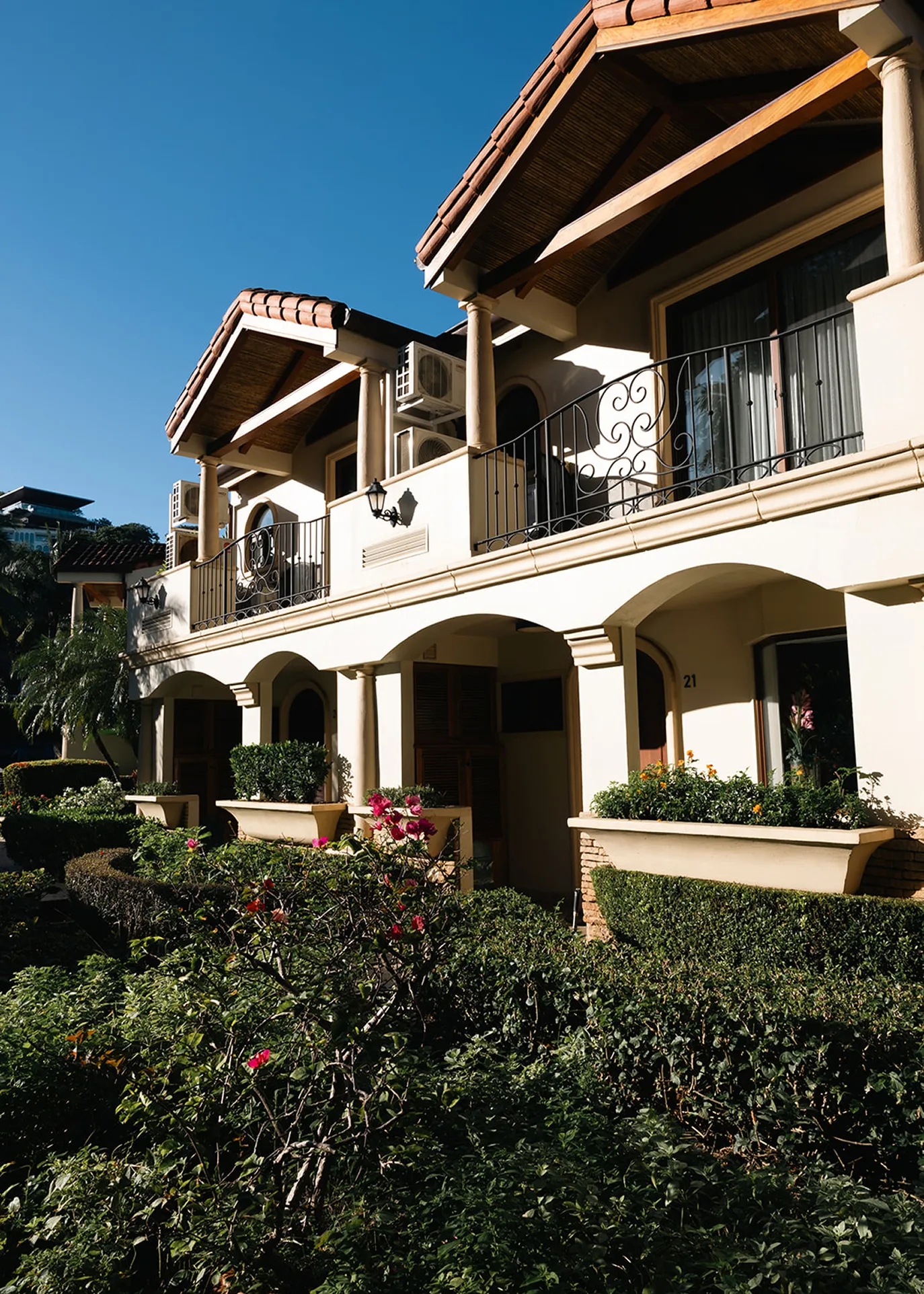 Terracotta-roofed villa exterior with arched walkways and flowering hedges at Ralia's Costa Rica retreat