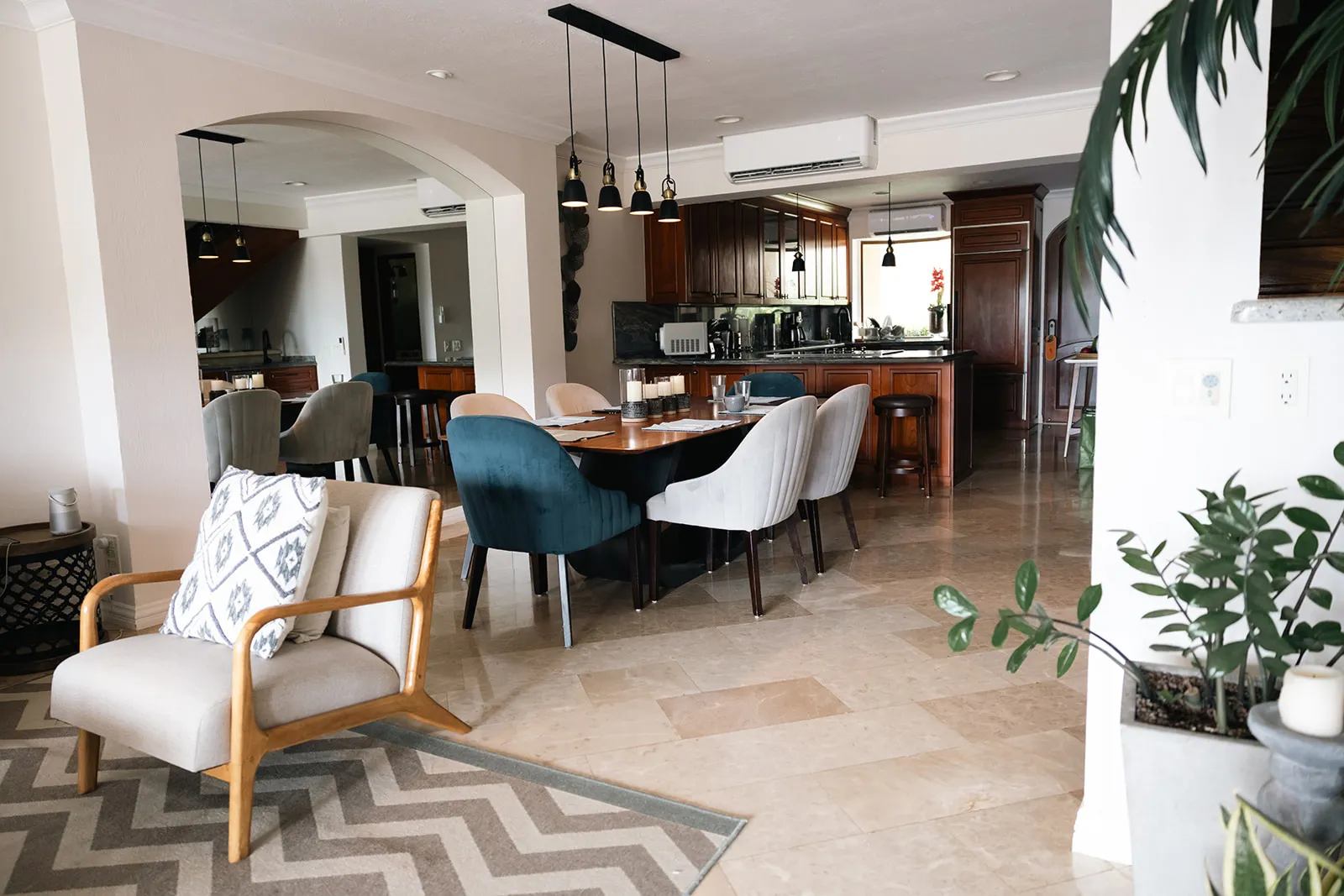 Open-plan living and dining area with a wood kitchen and potted palms inside the oceanfront villa