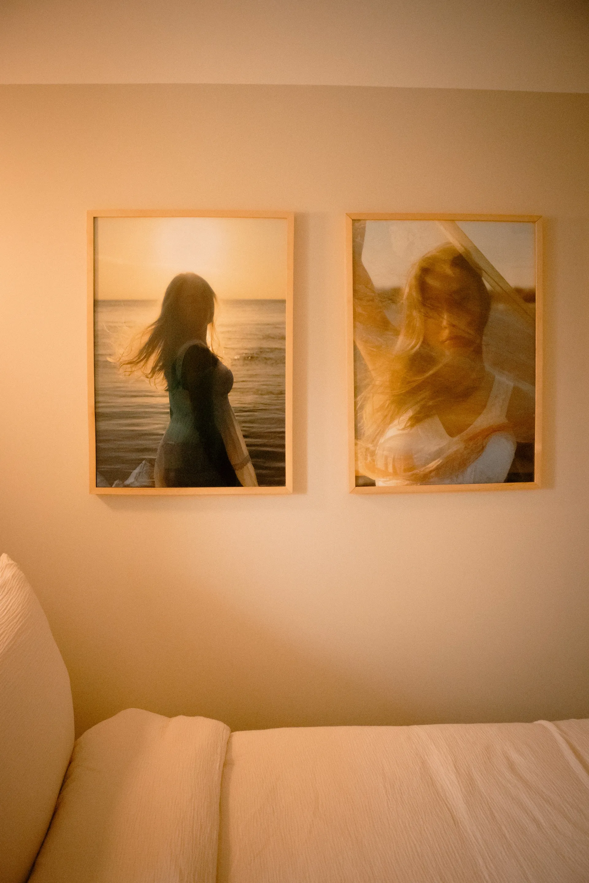 Two framed sunset beach photographs hanging above the bed in a guest room at La Maison Ralia Montreal