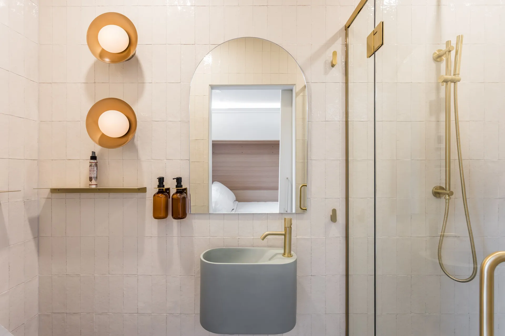 Guest bathroom with sage green basin, arched mirror, brass fixtures and walk-in shower at La Maison Ralia