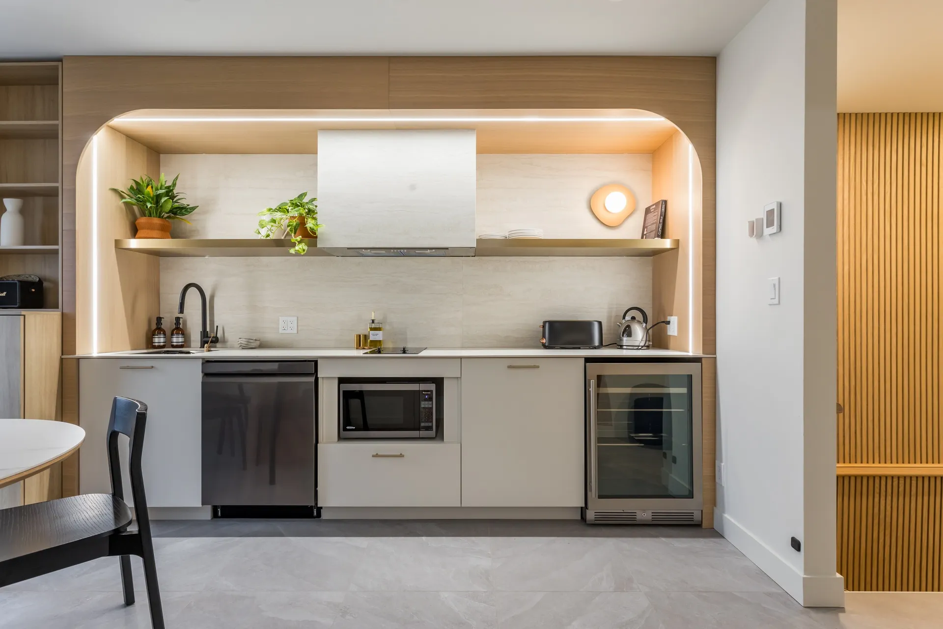 Kitchenette in an arched oak alcove with plants, wine fridge and dining table in a La Maison Ralia apartment