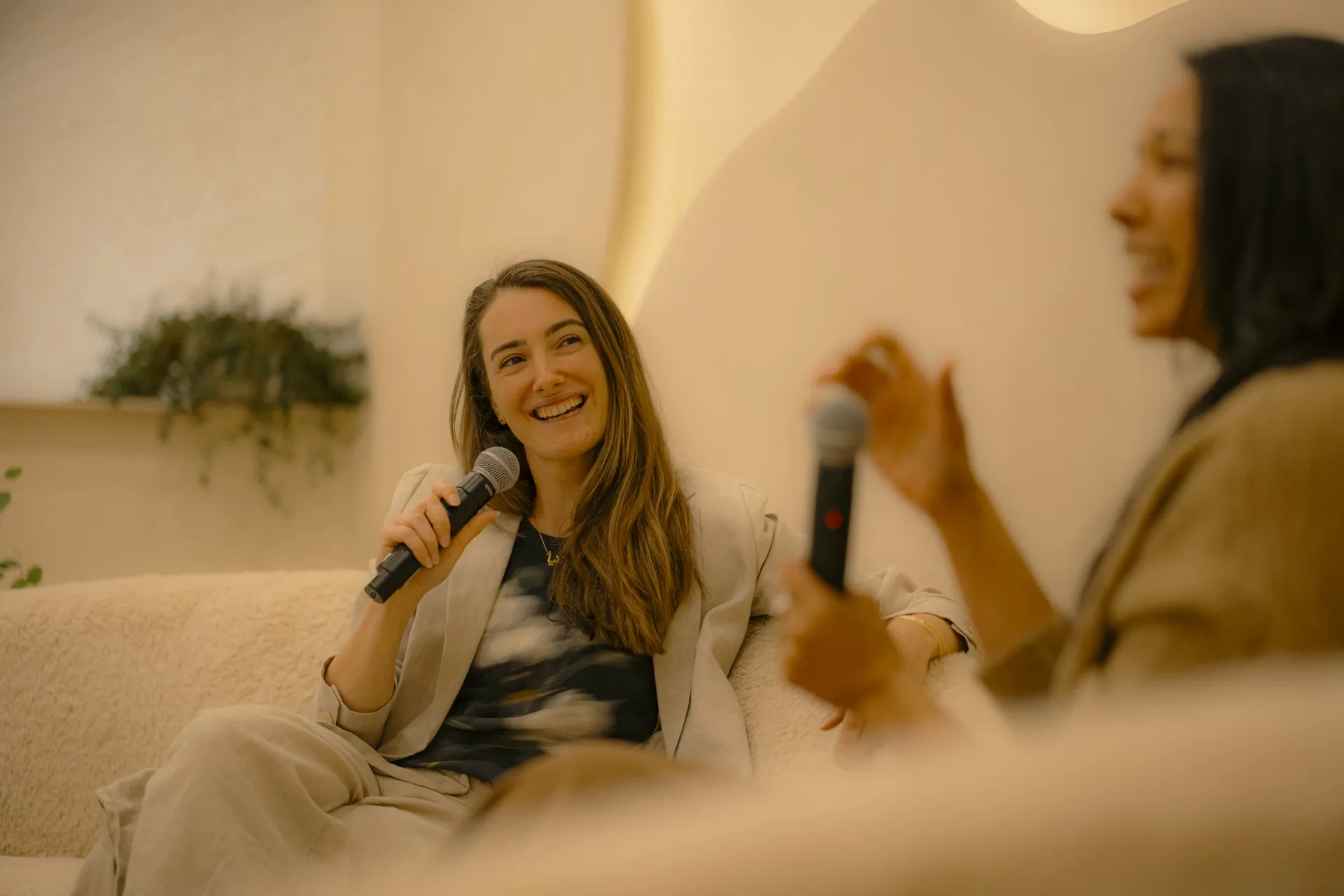 Smiling guest speaker holding a microphone during a panel conversation in the Connections space at La Maison Ralia