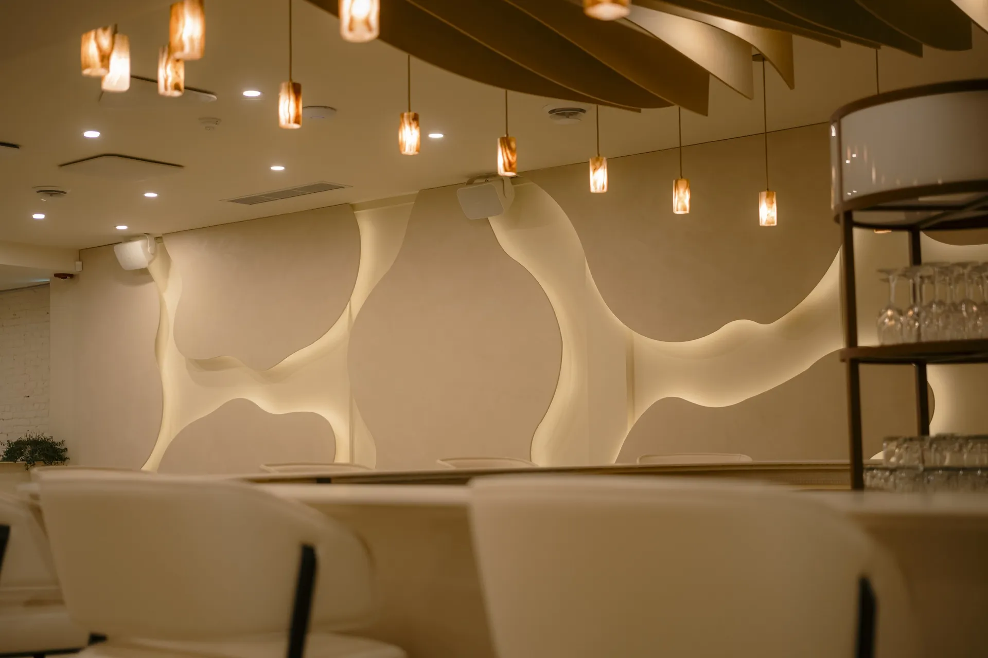 Sculpted white wall and pendant lighting in the Connections event space at La Maison Ralia Montreal