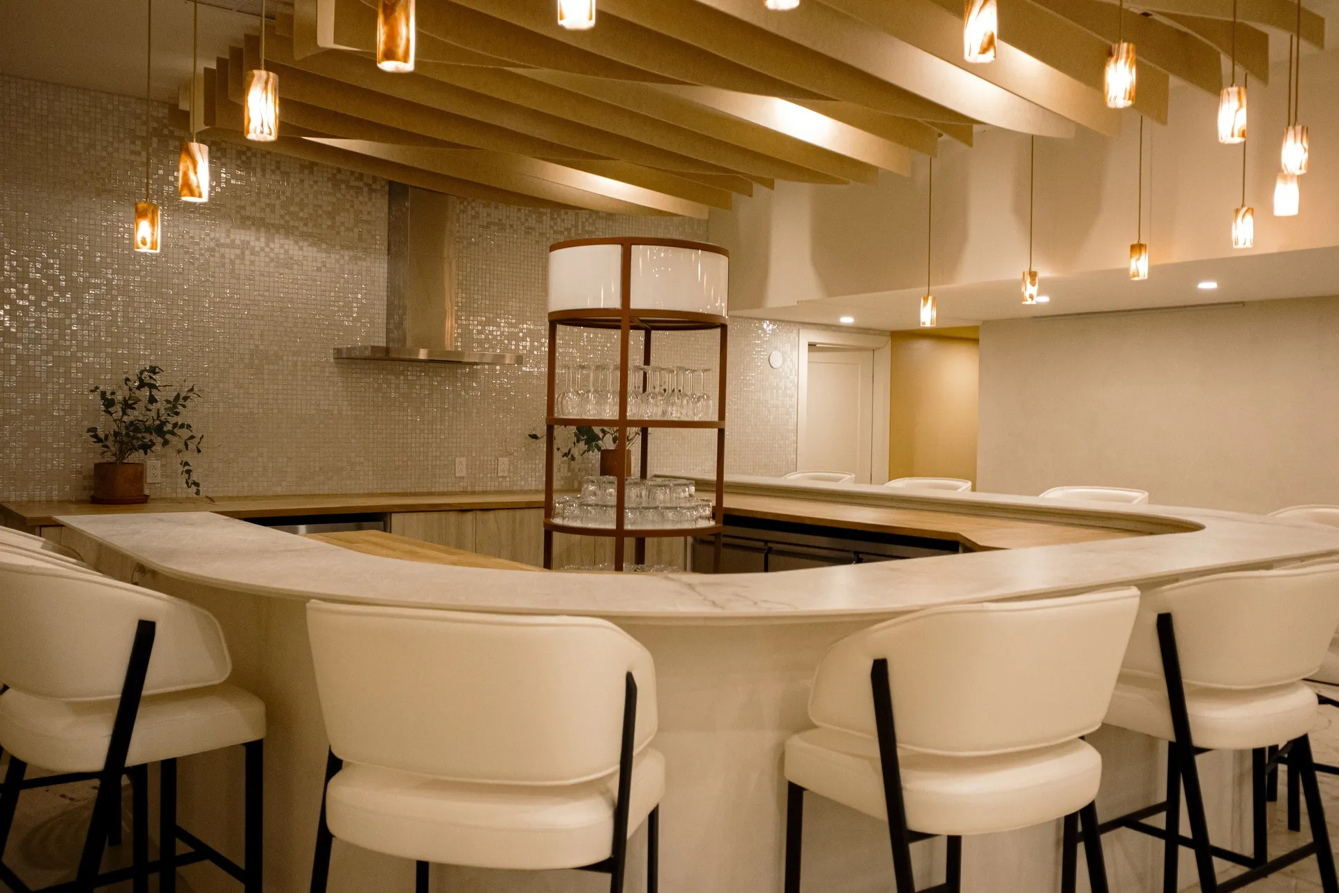 Curved bar with pendant lighting and upholstered stools in the Connections event space at La Maison Ralia Montreal