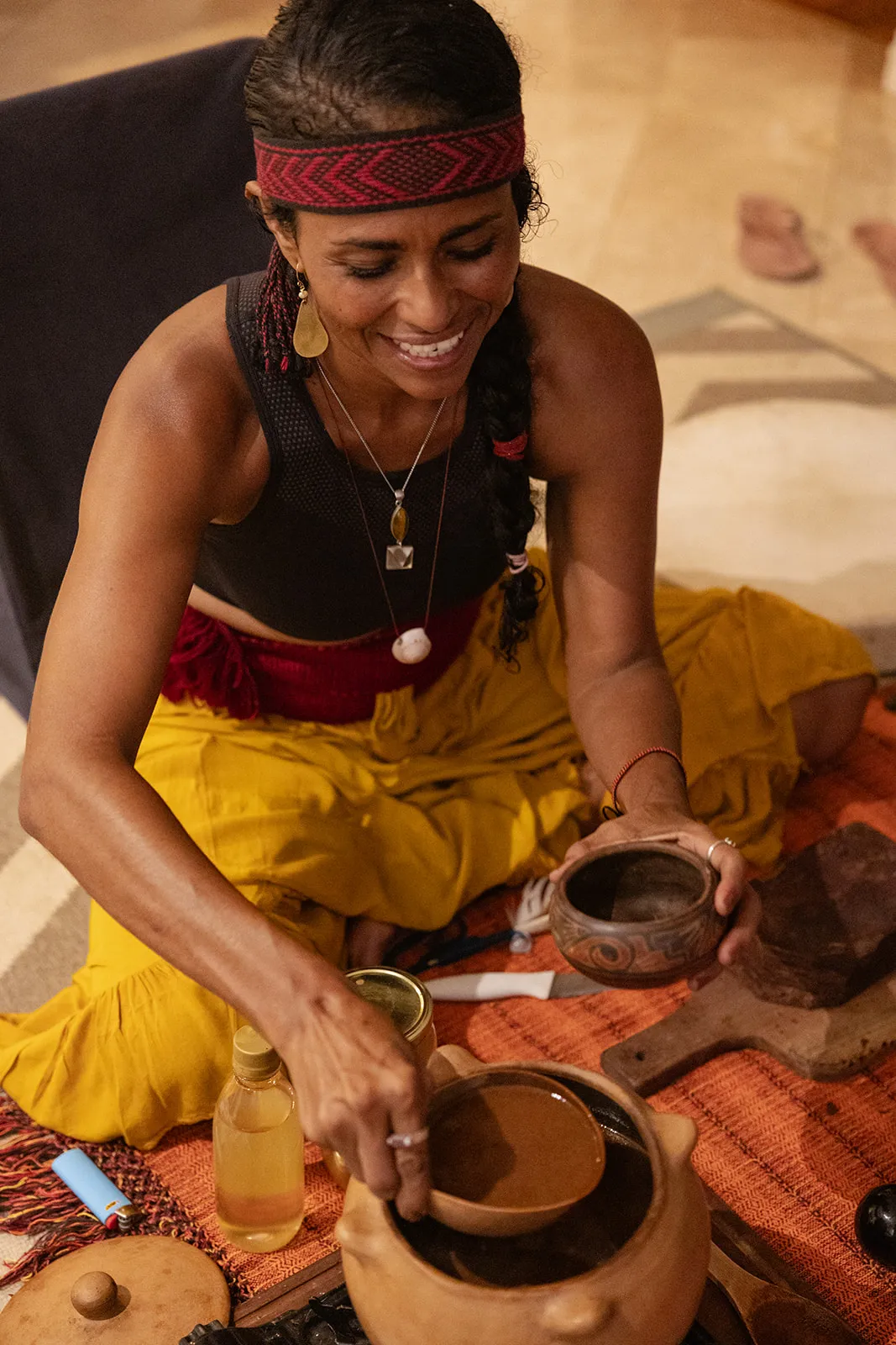 Facilitator smiling as she prepares cacao in clay bowls for a ceremony at the retreat