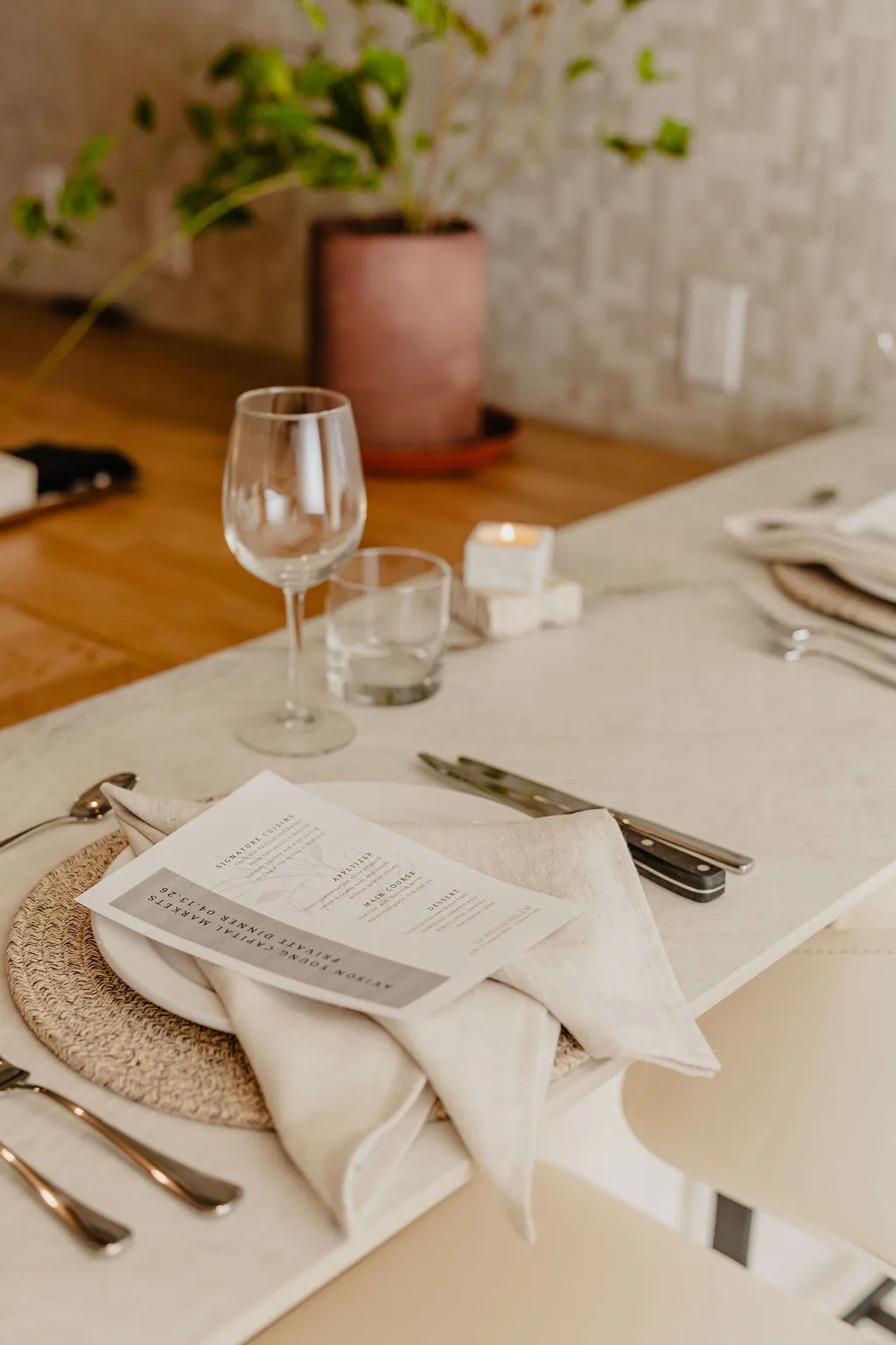 Place setting with linen napkin, printed menu card, wine glass and candle on a private dining table