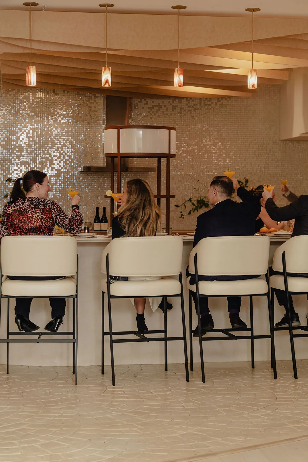 Guests toasting cocktails at the curved bar in the Connections event space at La Maison Ralia Montreal